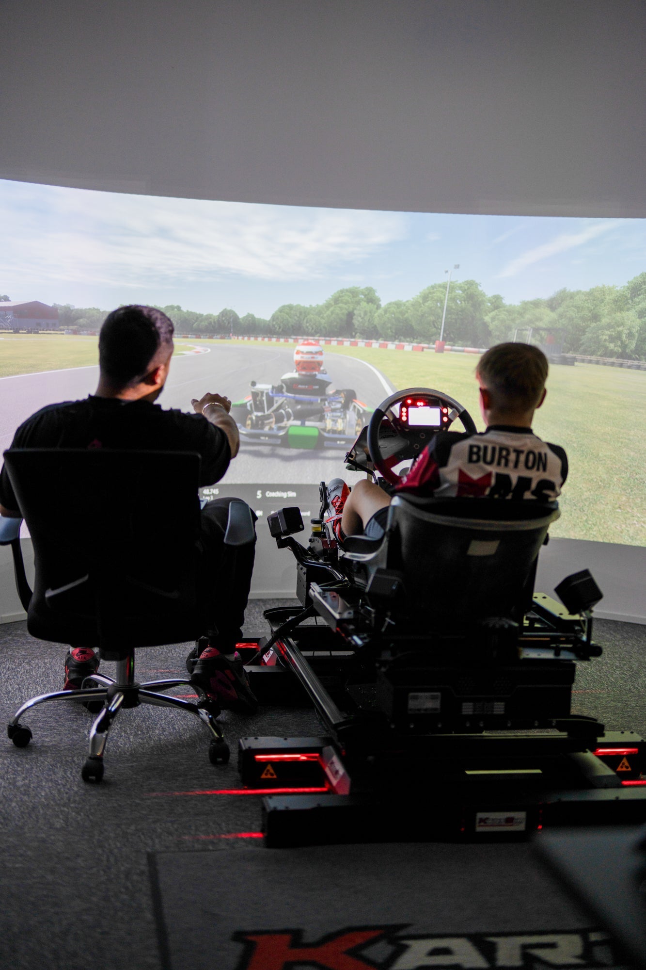 Professional kart simulator driver training session with race instructor on realistic racing track display