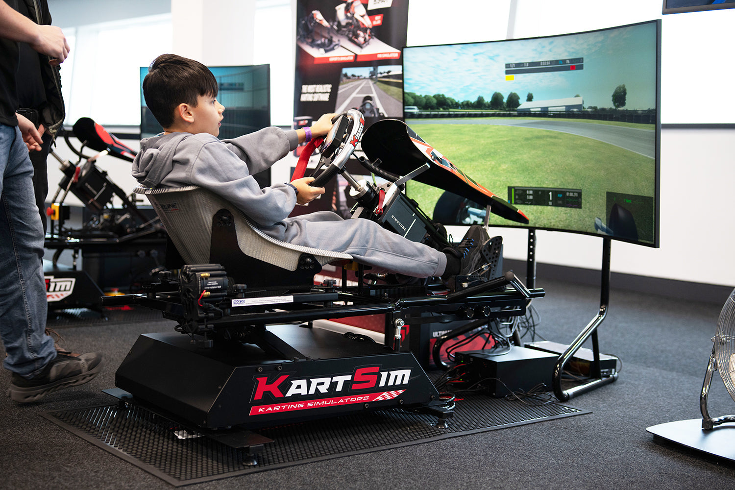 Young driver training on KartSim professional kart simulator with motion platform and racing HUD display
