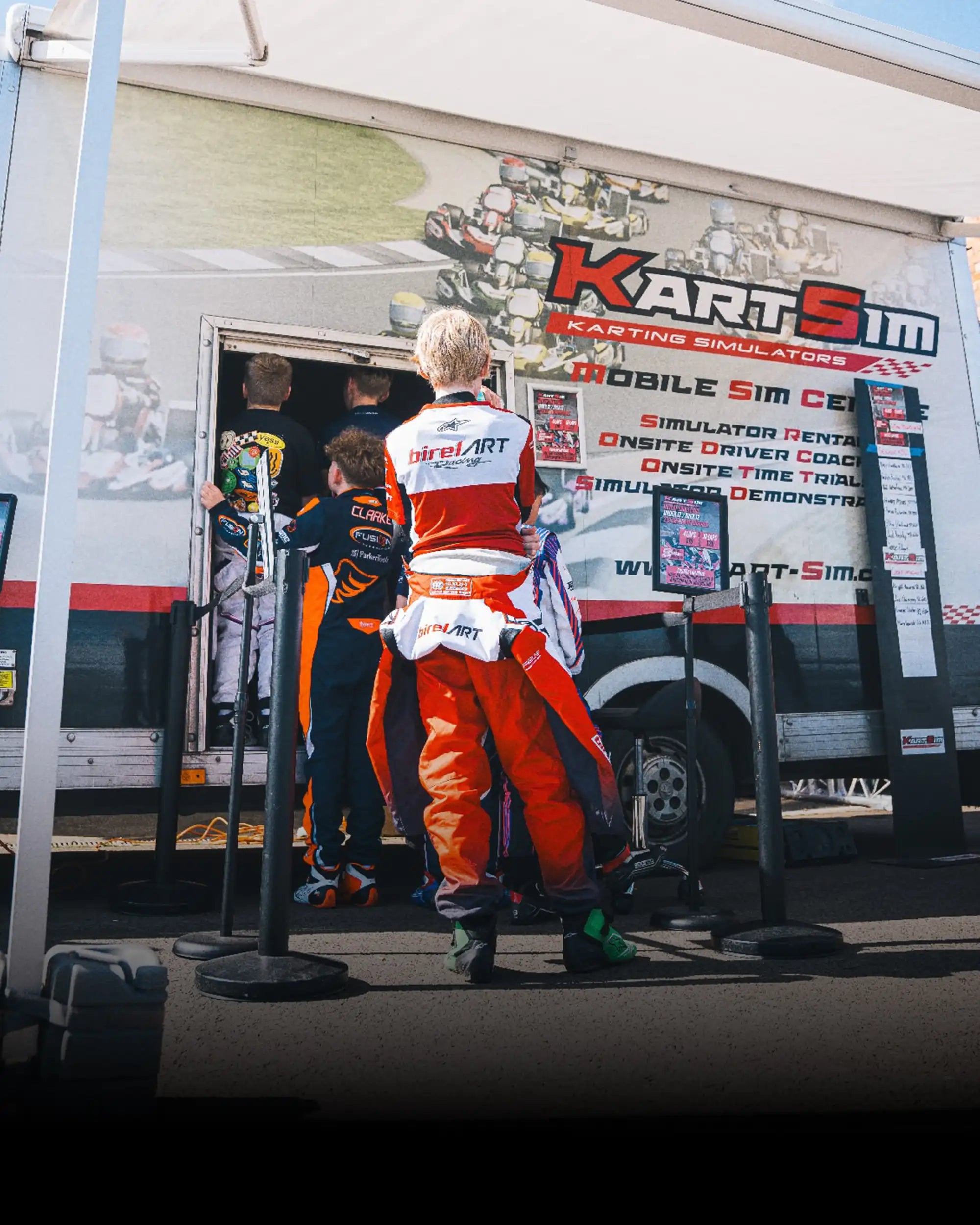 Kart drivers in racing suits entering mobile kart racing simulator center for professional training