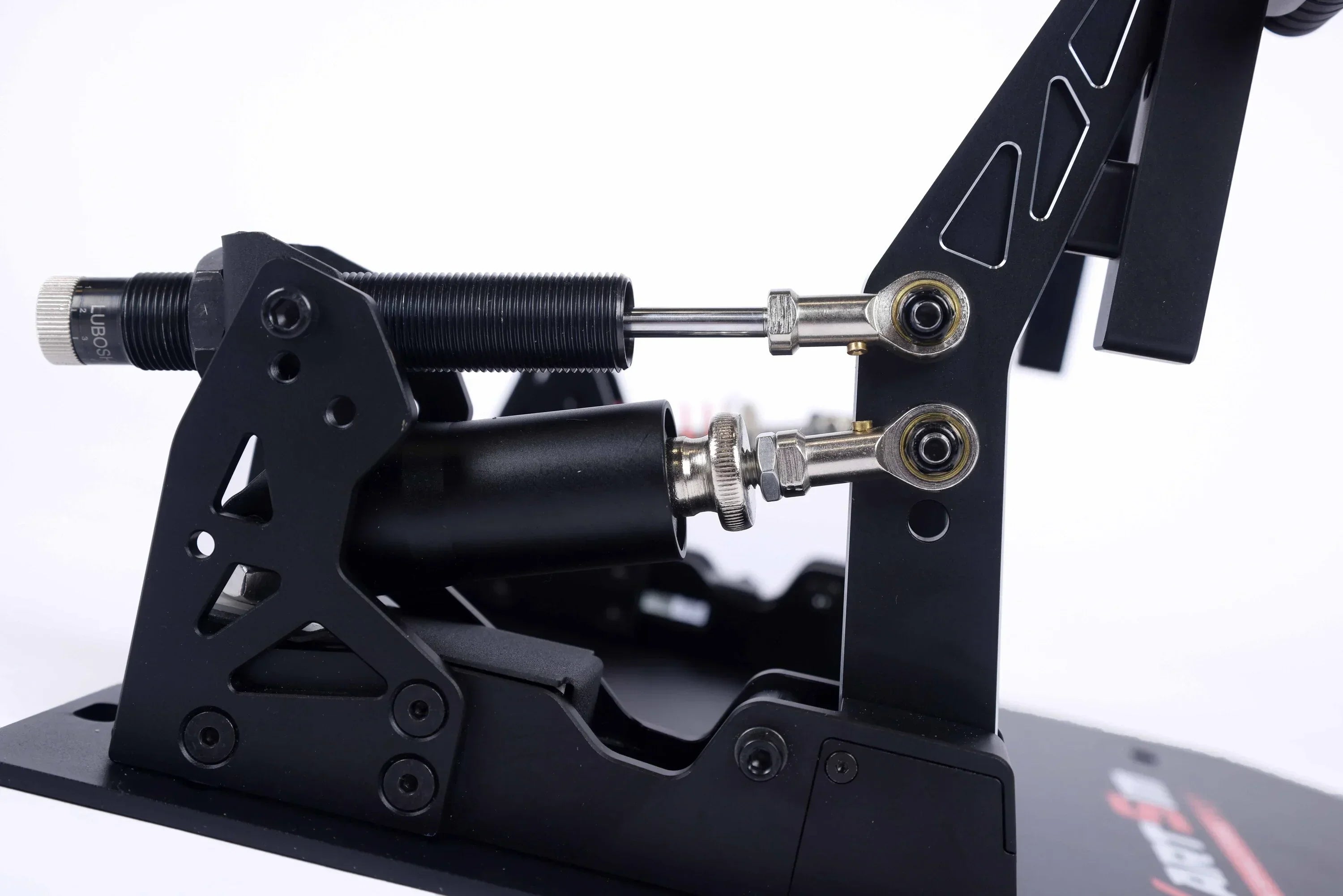 Close-up view of KartSim eSports pedal assembly showing load cell damper system, precision machined metal components, and rod-end joints for adjustable resistance.