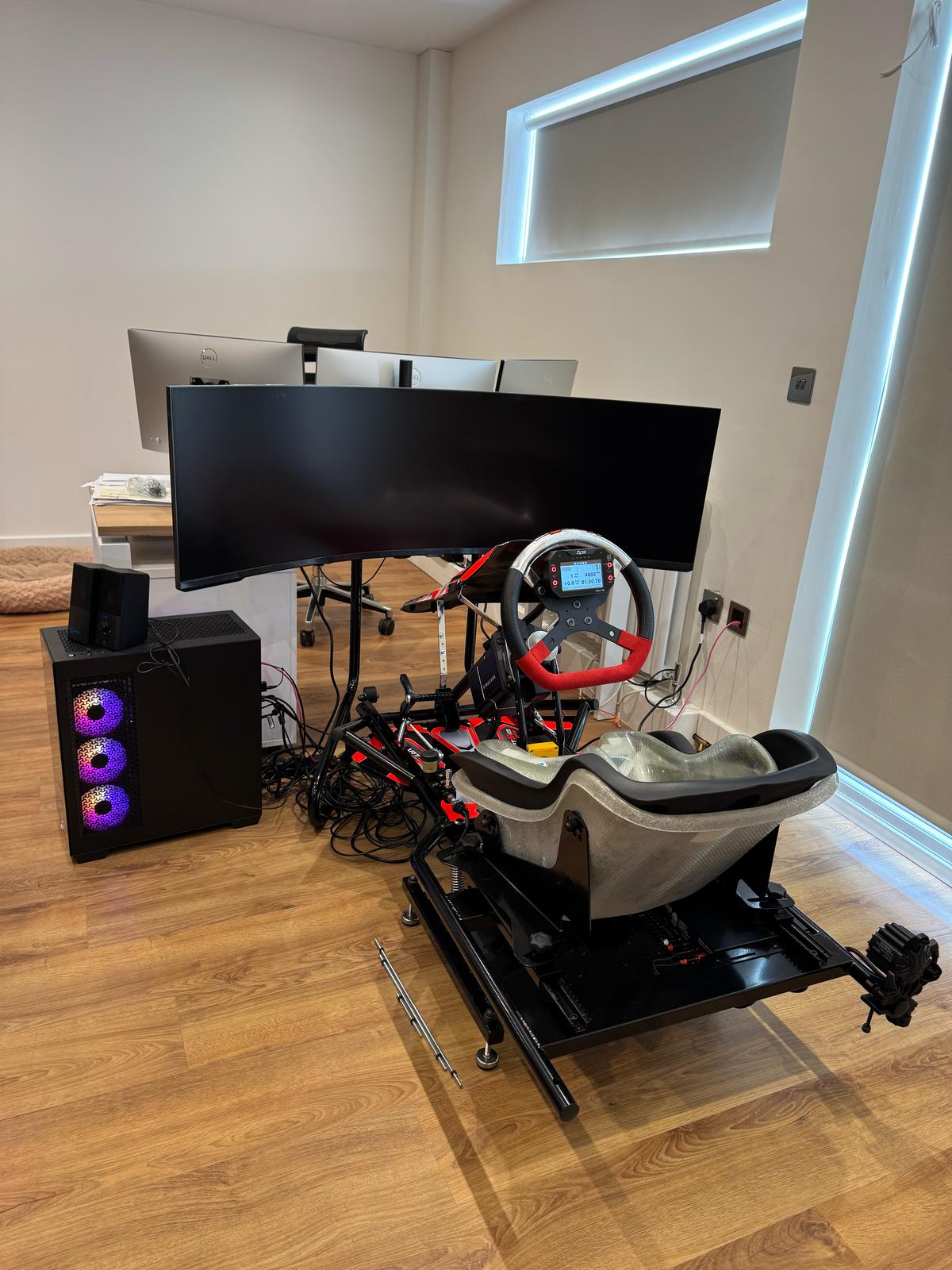 KartSim Pro Simulator setup in an office space, featuring a full kart chassis, direct drive wheel, triple-screen monitor and professional-grade simulation hardware for driver coaching and at-home training.