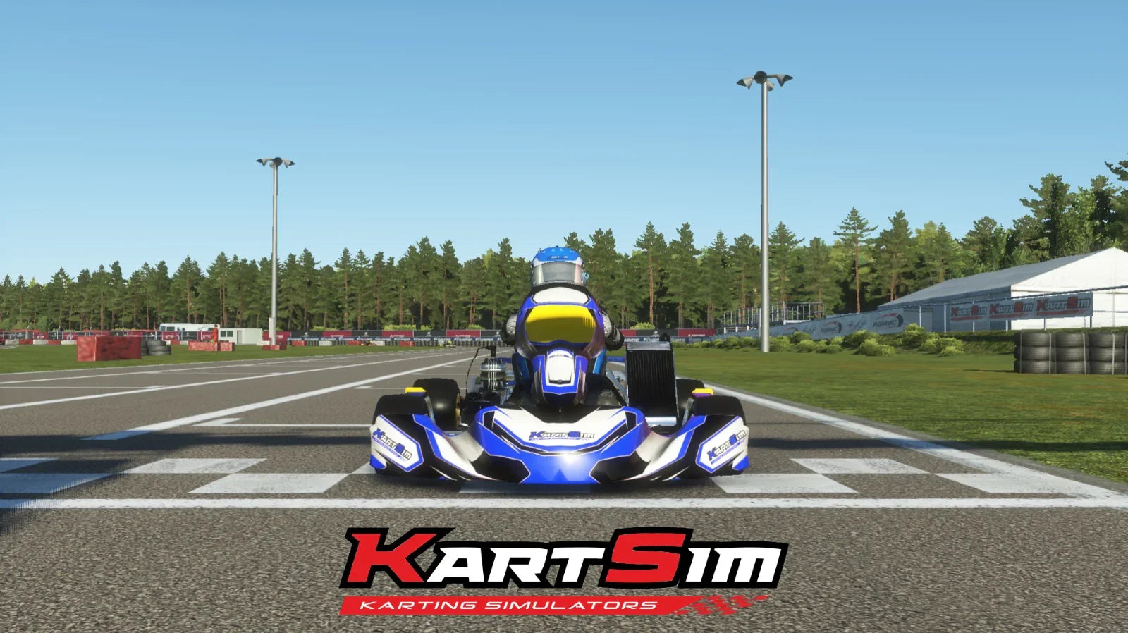 KartSim Ultimate software screenshot showing a virtual kart on the starting grid, centered with a blue and yellow livery, surrounded by realistic trackside scenery and branded barriers.