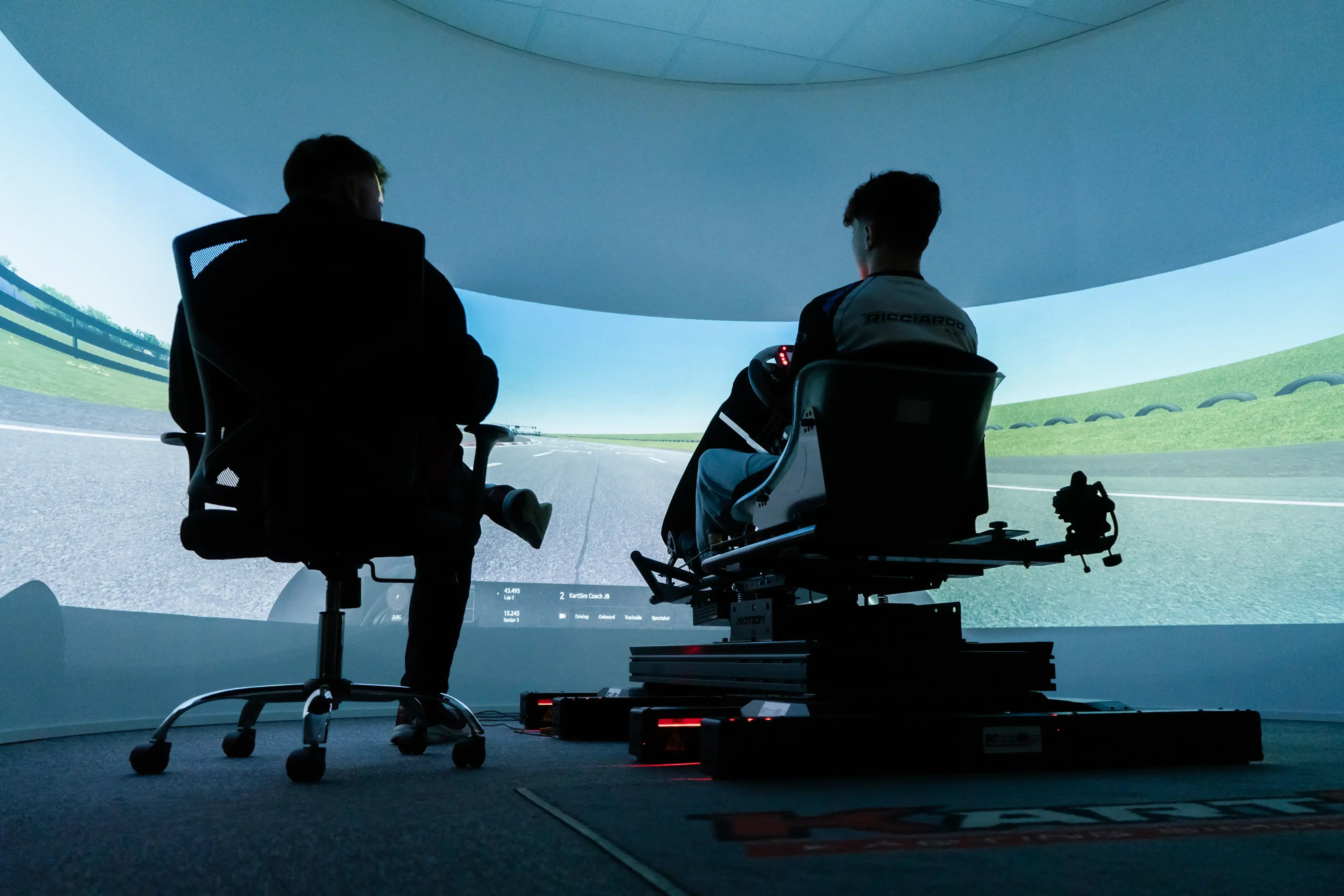 Professional KartSim driver coaching on motion simulator with real-time track feedback and coach support.