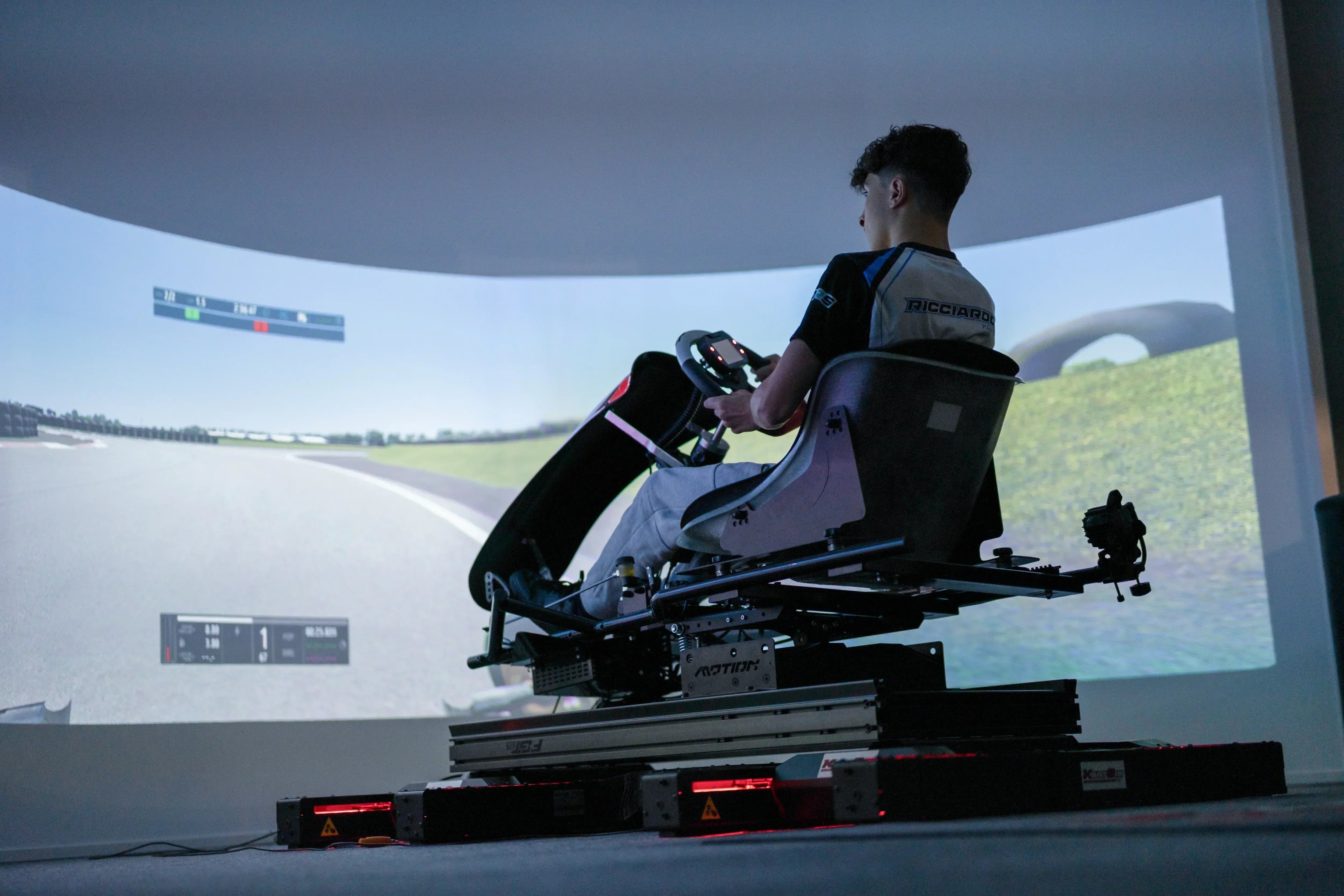 Driver in professional kart simulator rig with motion platform and realistic racing interface