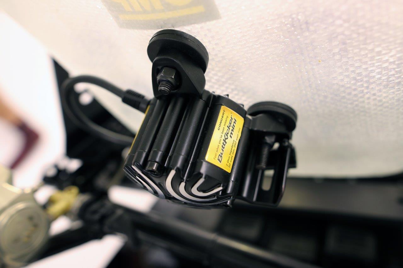 ButtKicker Mini haptic feedback device mounted on a KartSim racing simulator to replicate realistic kart vibrations and engine rumble