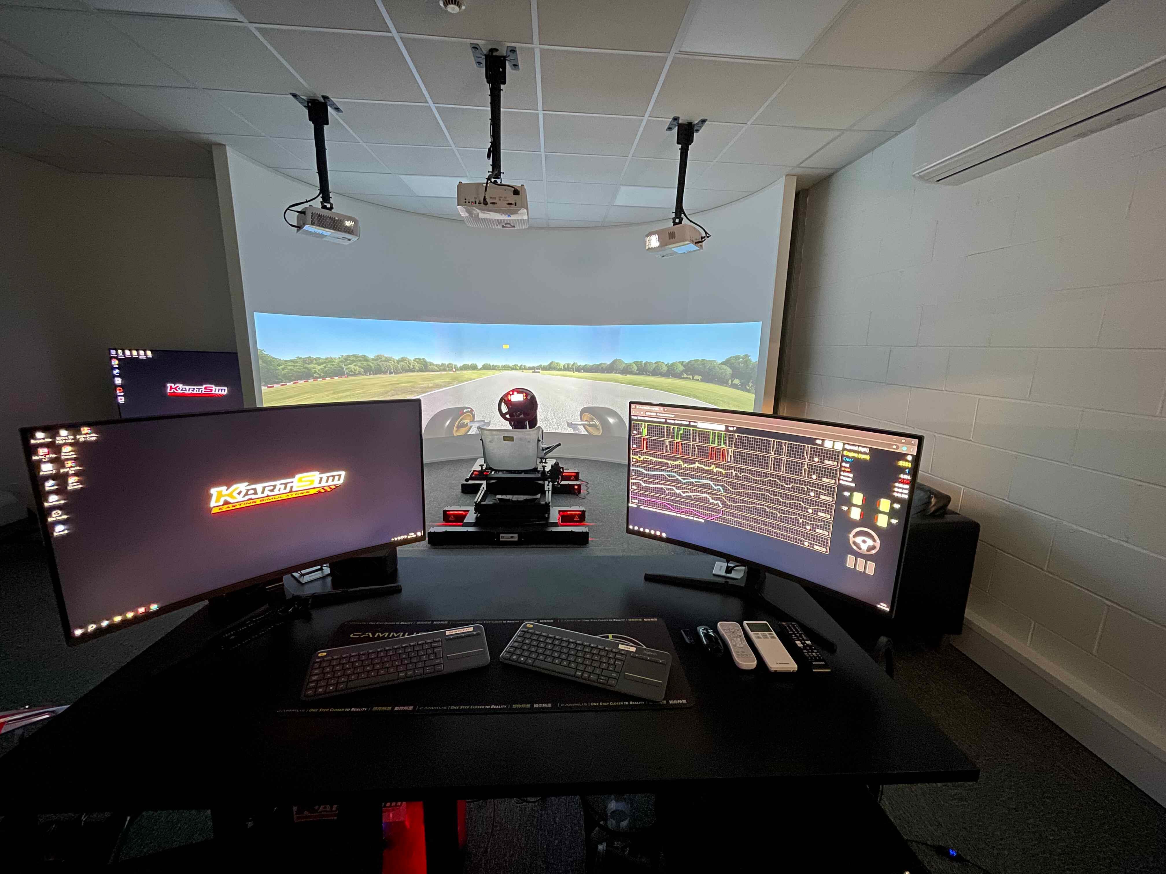 KartSim simulator room featuring full-motion kart sim with wraparound projection and dual-monitor telemetry station for real-time driver performance analysis and coaching