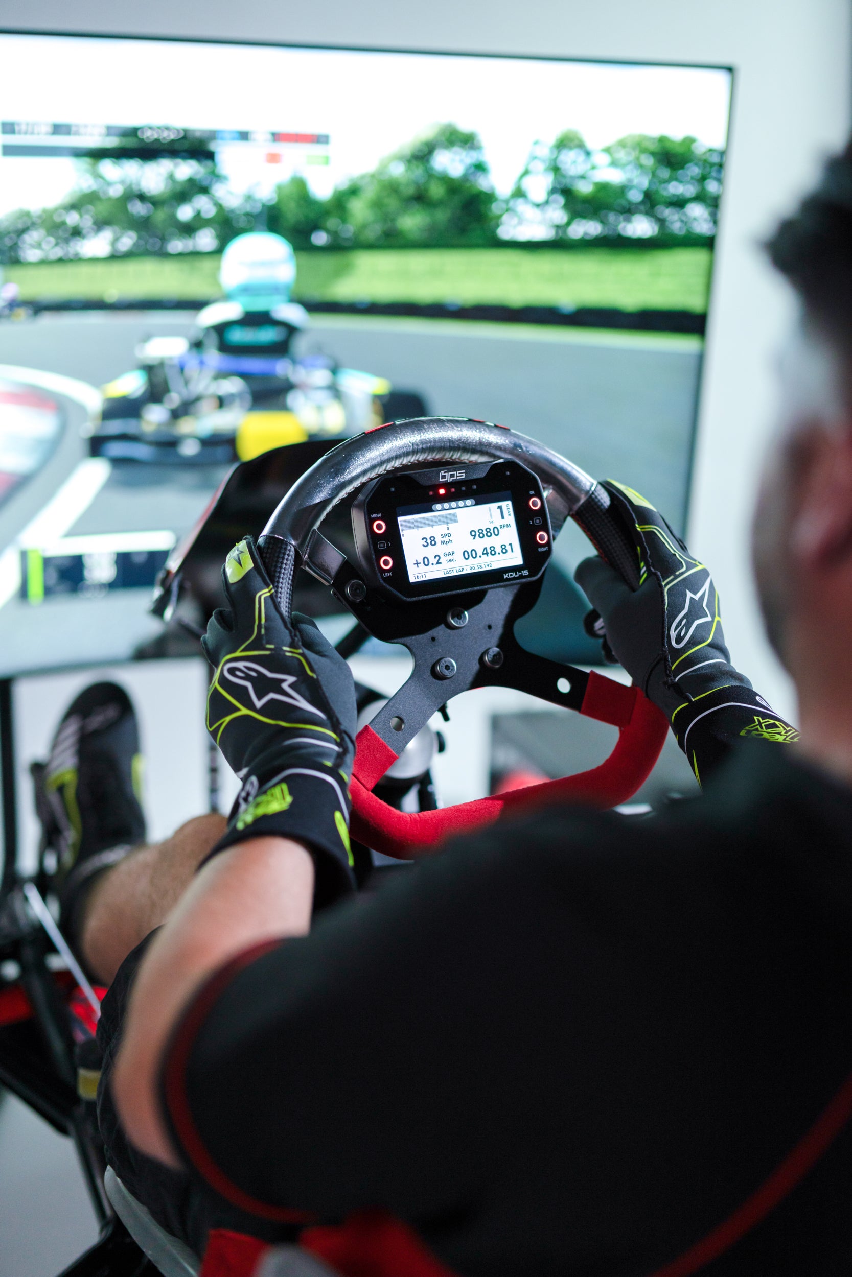Back view of KartSim ProSim racing simulator cockpit with ergonomic seat, steering wheel and monitor, and pedal set