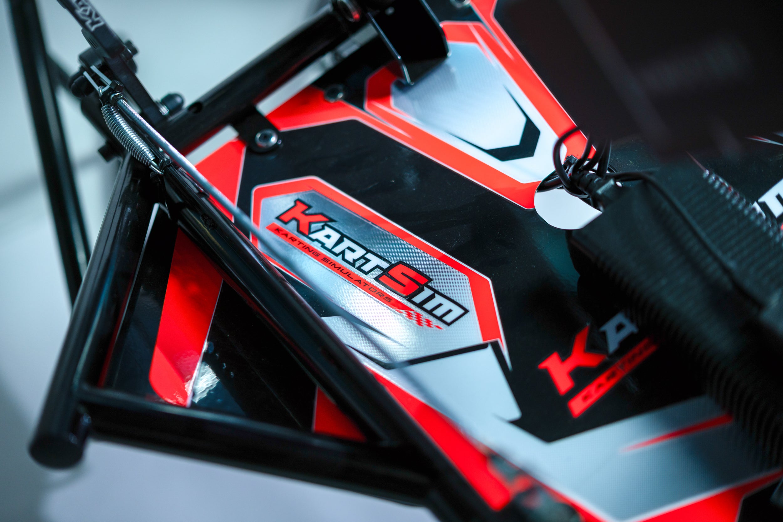 Close-up of KartSim racing simulator chassis showing logo decal and structural frame with red and black accents