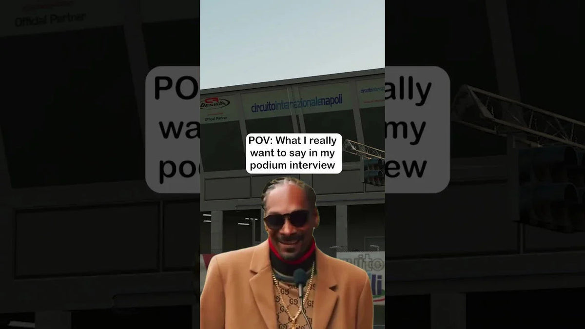 Person with sunglasses and microphone at kart racing podium, circuit signage in background, podium interview humor