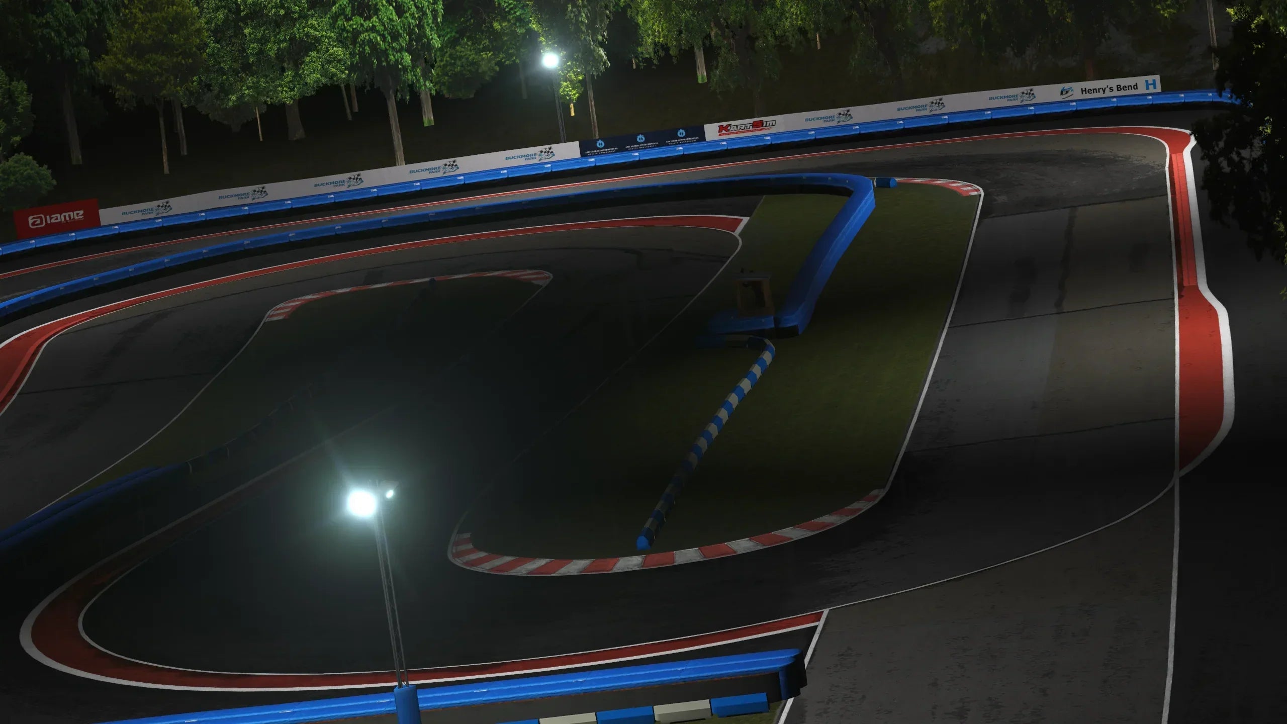 The Illuminated Hairpin – A dramatic overhead night-time view of the tight hairpin, fully lit and surrounded by Buckmore’s distinctive blue-and-white barriers.