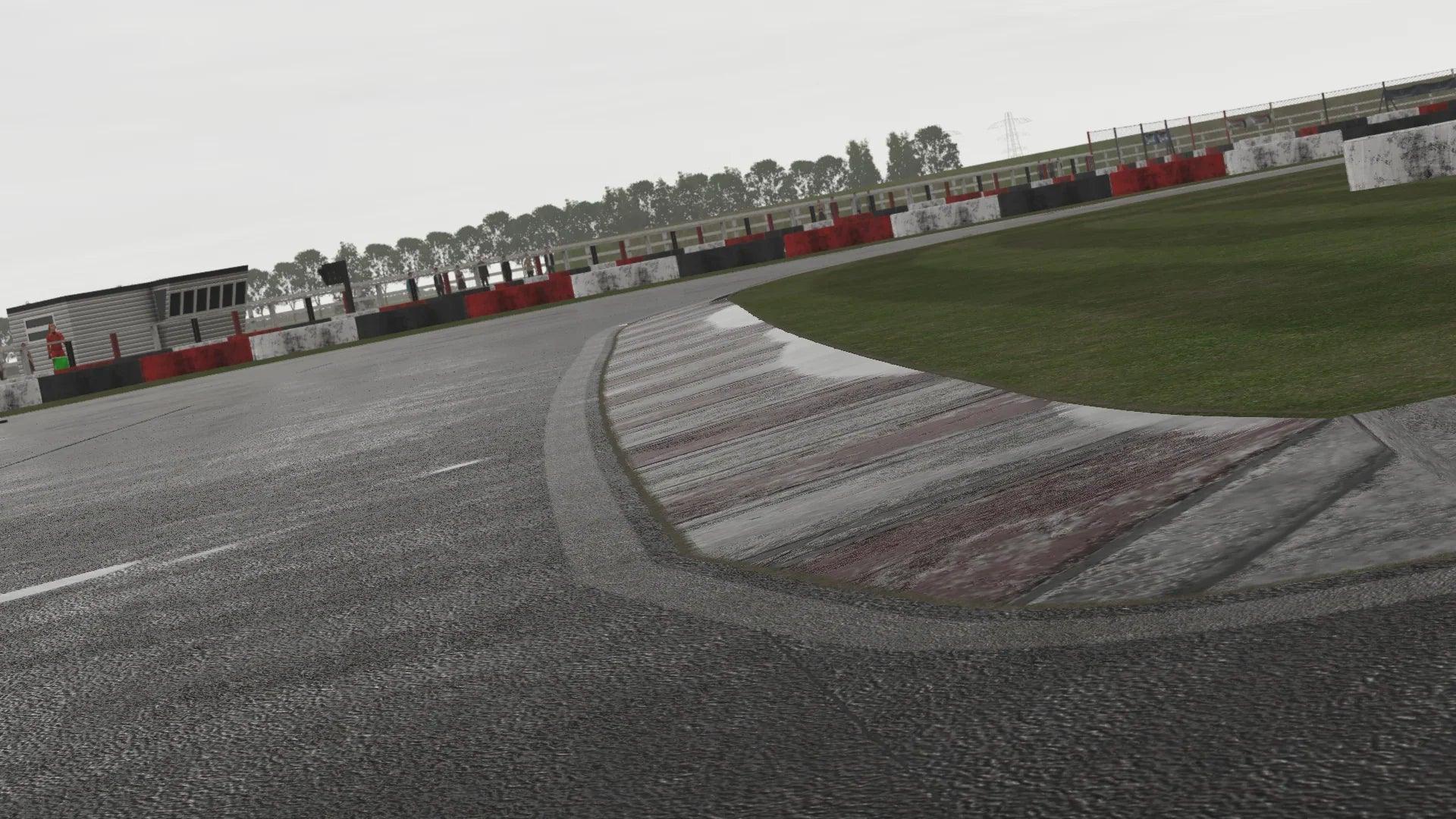 Track-level view of a kerb apex at Lydd during rain simulation, showcasing detailed texture and surface grip changes.