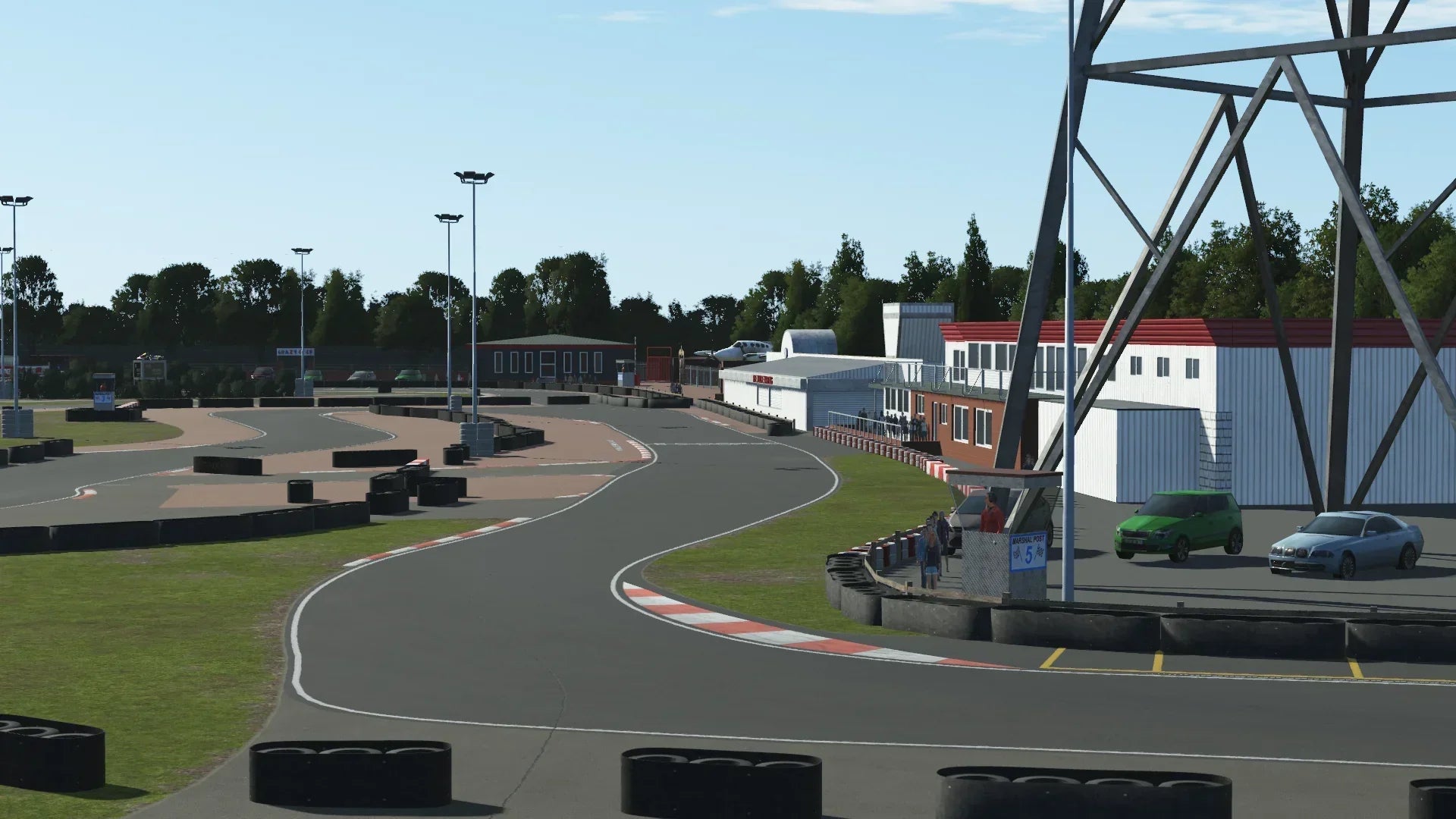 A view down the back straight of KartSim Rye House track with multiple corners ahead, the clubhouse, pit lane, and observation areas visible.