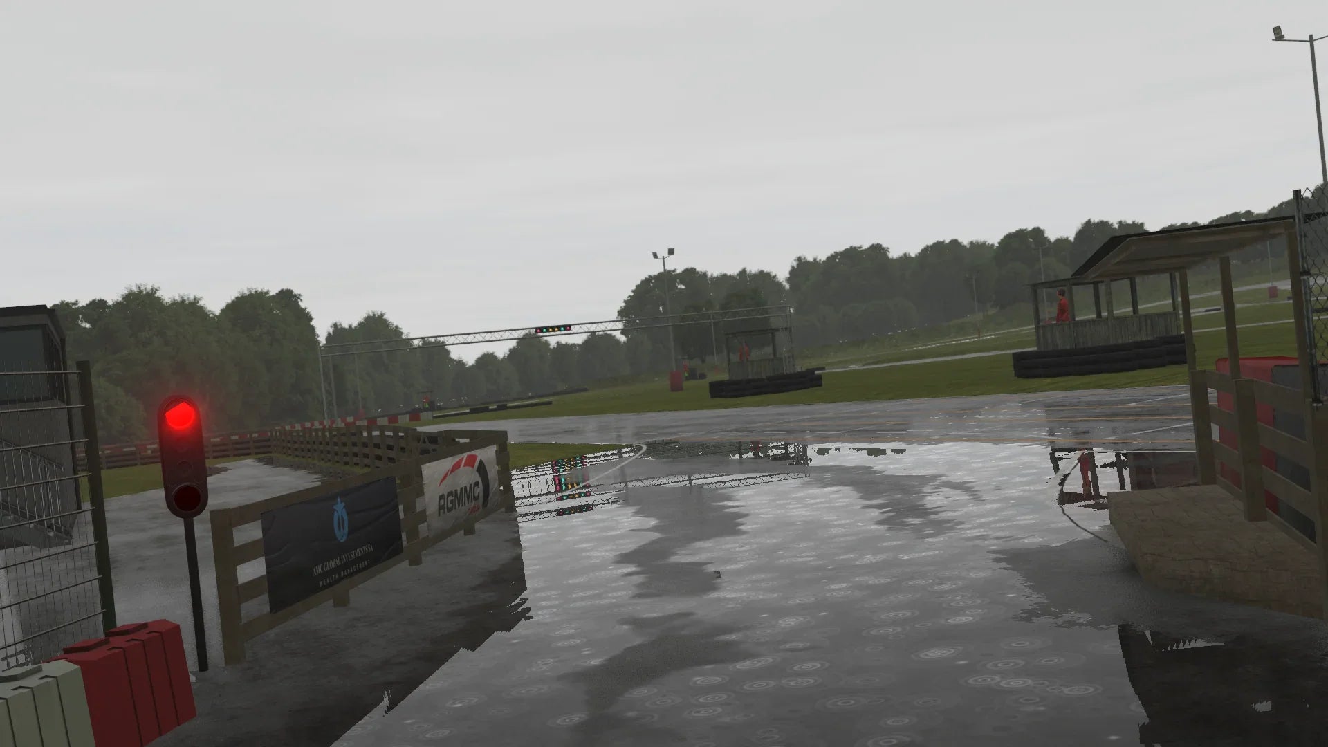 KartSim Whilton Mill wet pit lane entry – Rainy day at Whilton Mill in KartSim, with reflections on the wet surface and a red pit exit light glowing.