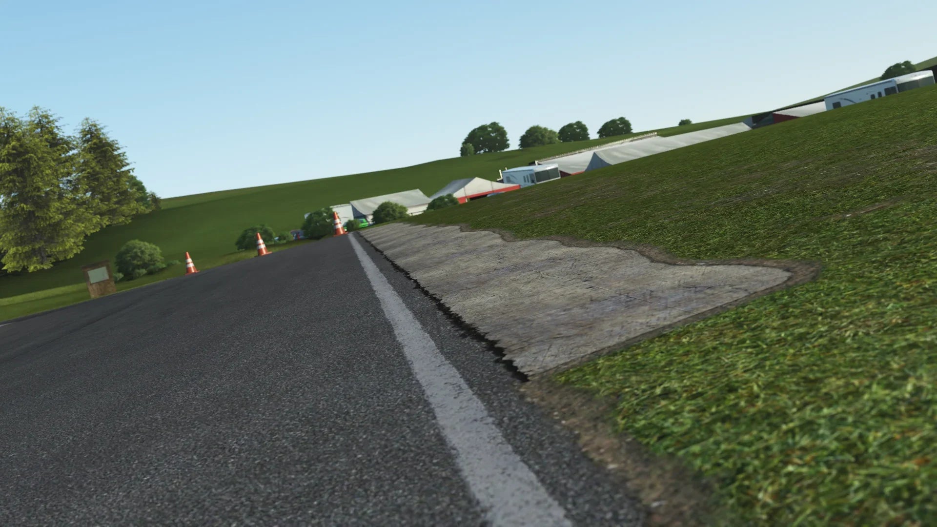 Close-up of GYG kerbing – KartSim’s detail shows the worn concrete kerb on the edge of the racing line, with the paddock tents and rolling hills in the background.