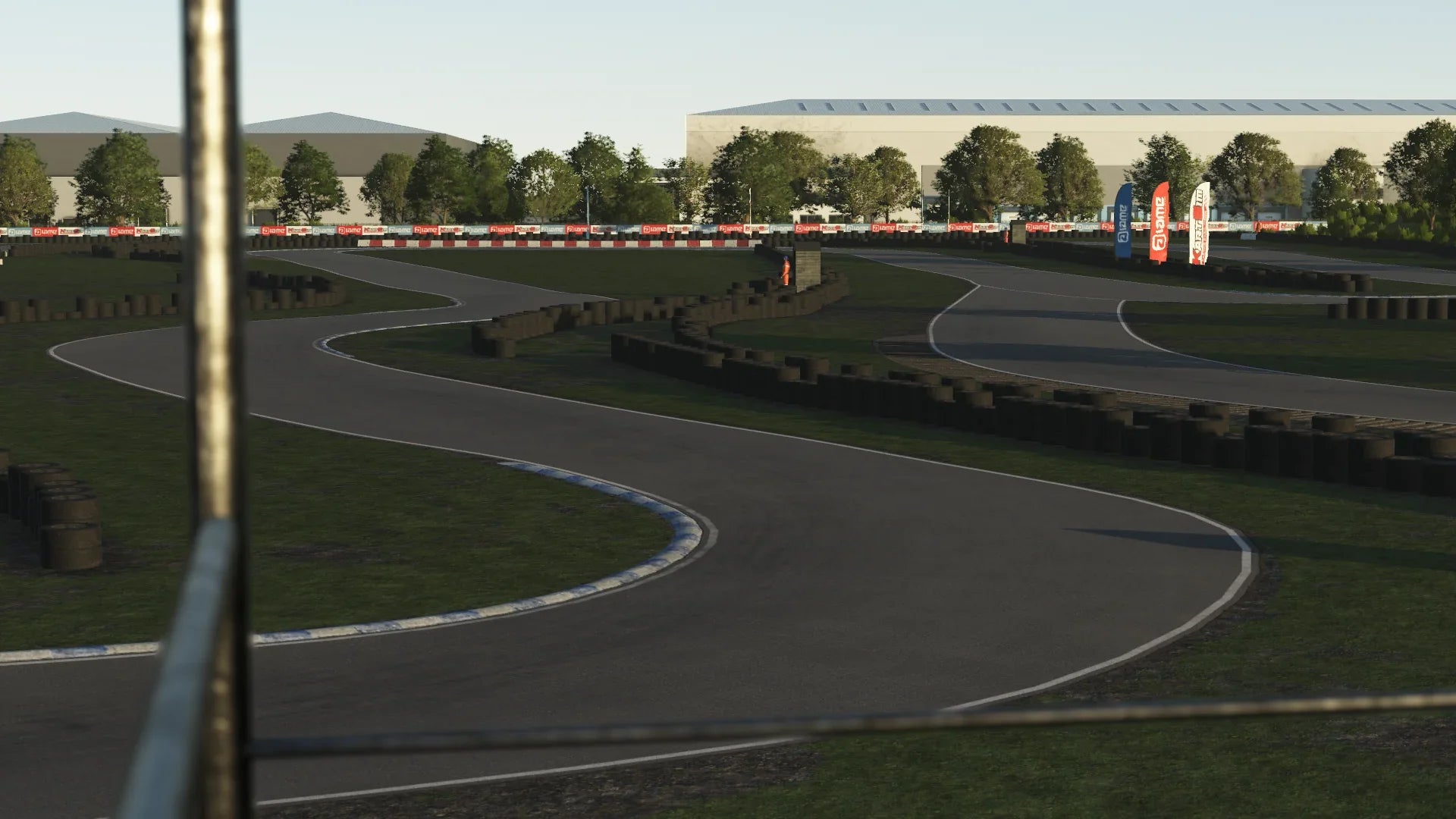 High-speed corner at Hooton Park in KartSim – A sharp bend with blue-and-white kerbs, tyre walls in the background, and lush greenery surrounding the circuit.
