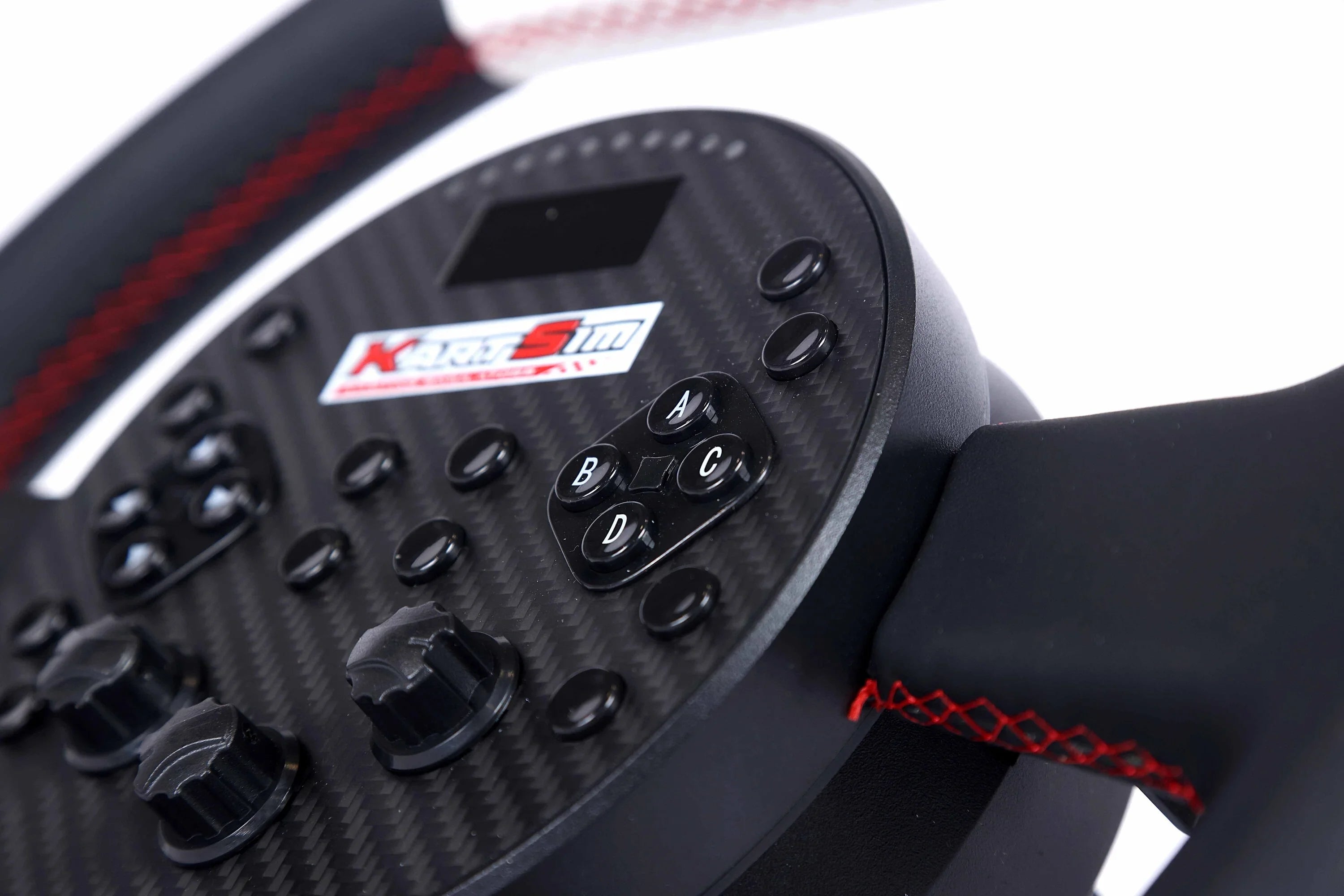 Close-up of the KartSim eSports racing wheel showing carbon fiber finish, customizable rotary dials, labeled buttons (A–D), and stitched red grip detail.
