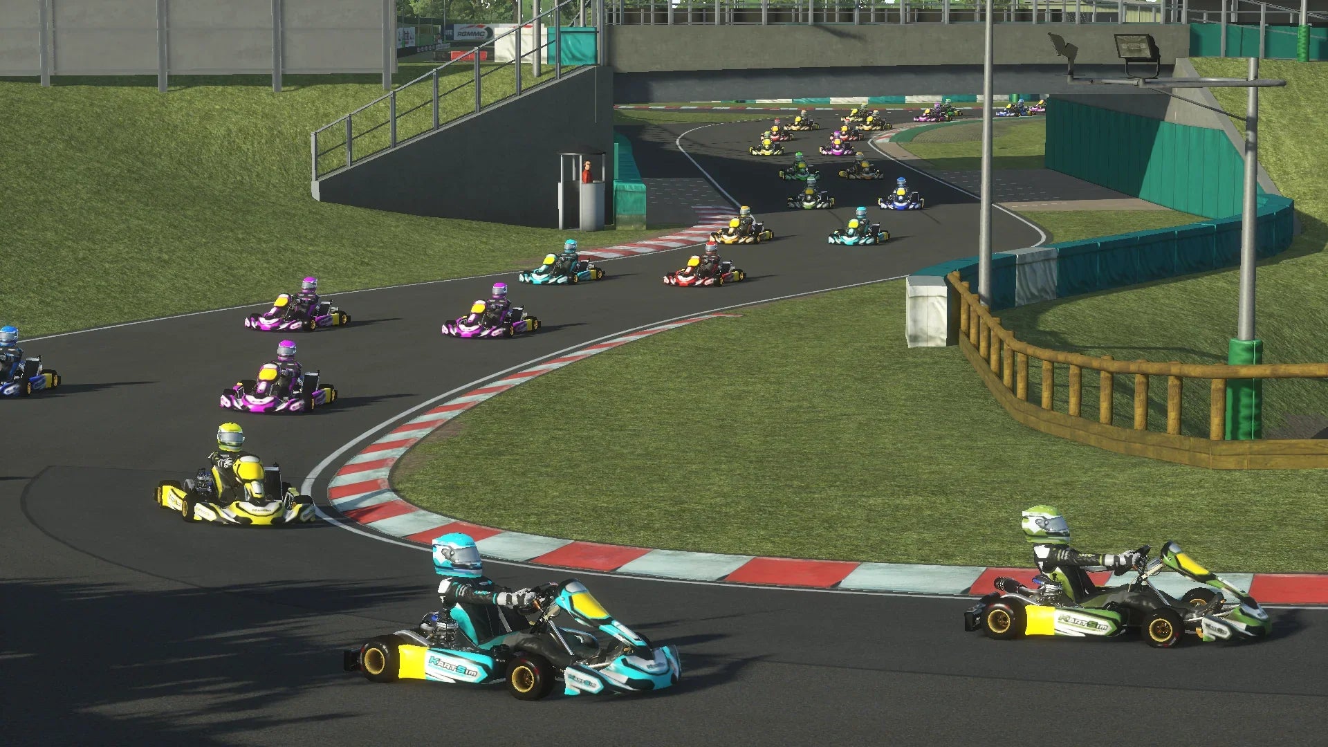 A pack of drivers race through the first corner at PFI International on KartSim, featuring realistic kart models and dynamic racing action under the bridge.