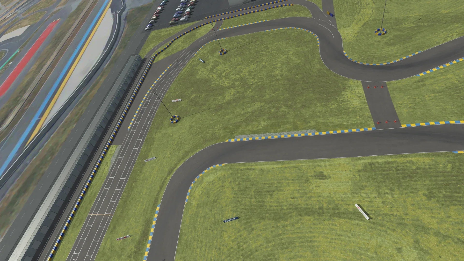 KartSim software render of a Le Mans–style track section, showing the pit lane on the left, winding asphalt race line with blue-and-yellow curbs, and grassy infield areas under a cloudy sky.