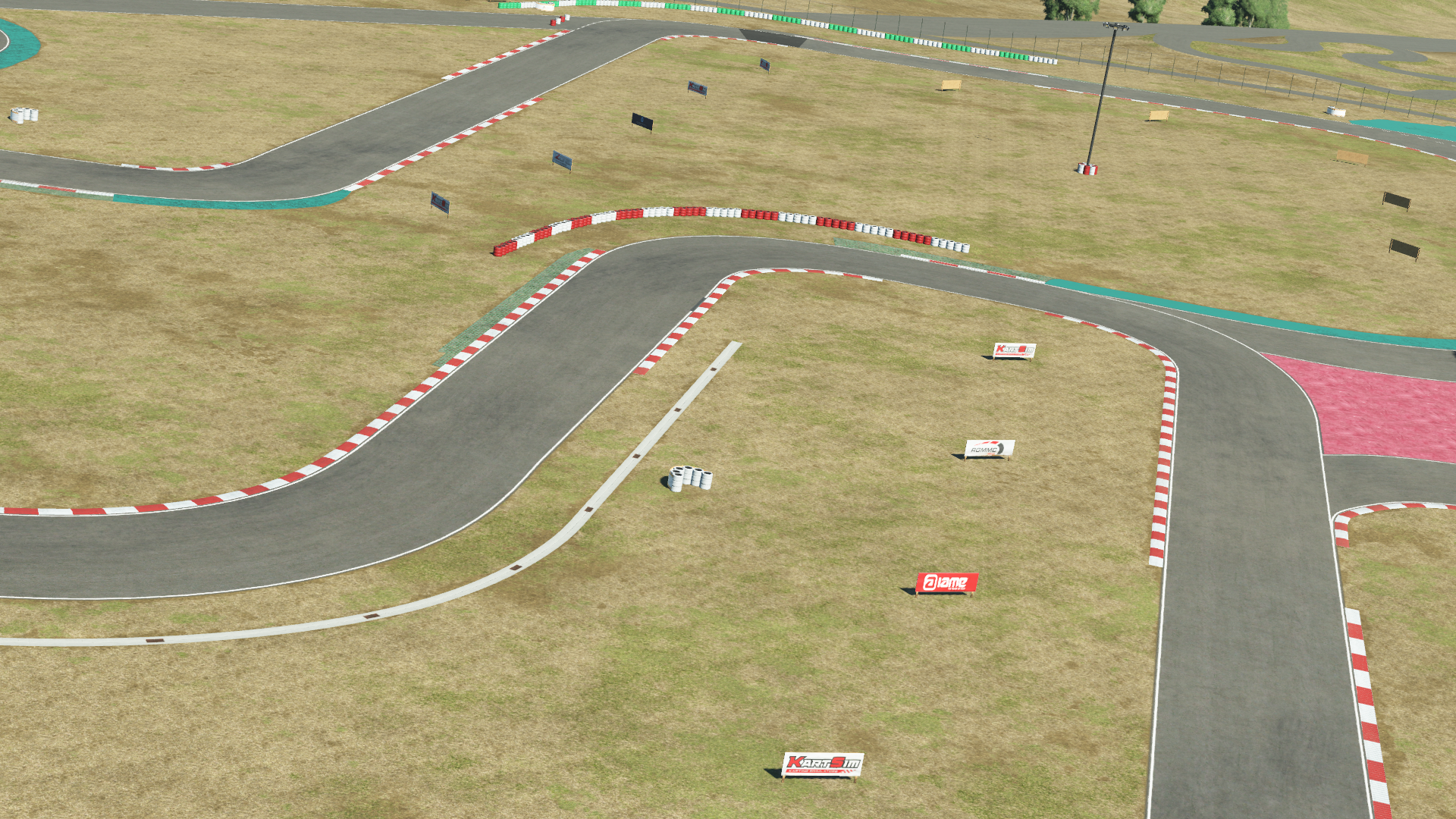 KartSim software rendering of Portimão kart track’s complex S-bend section, featuring red-and-white kerbs, dry grassy runoff areas dotted with small directional signs, turquoise runoff zones, and a clear sky overhead.