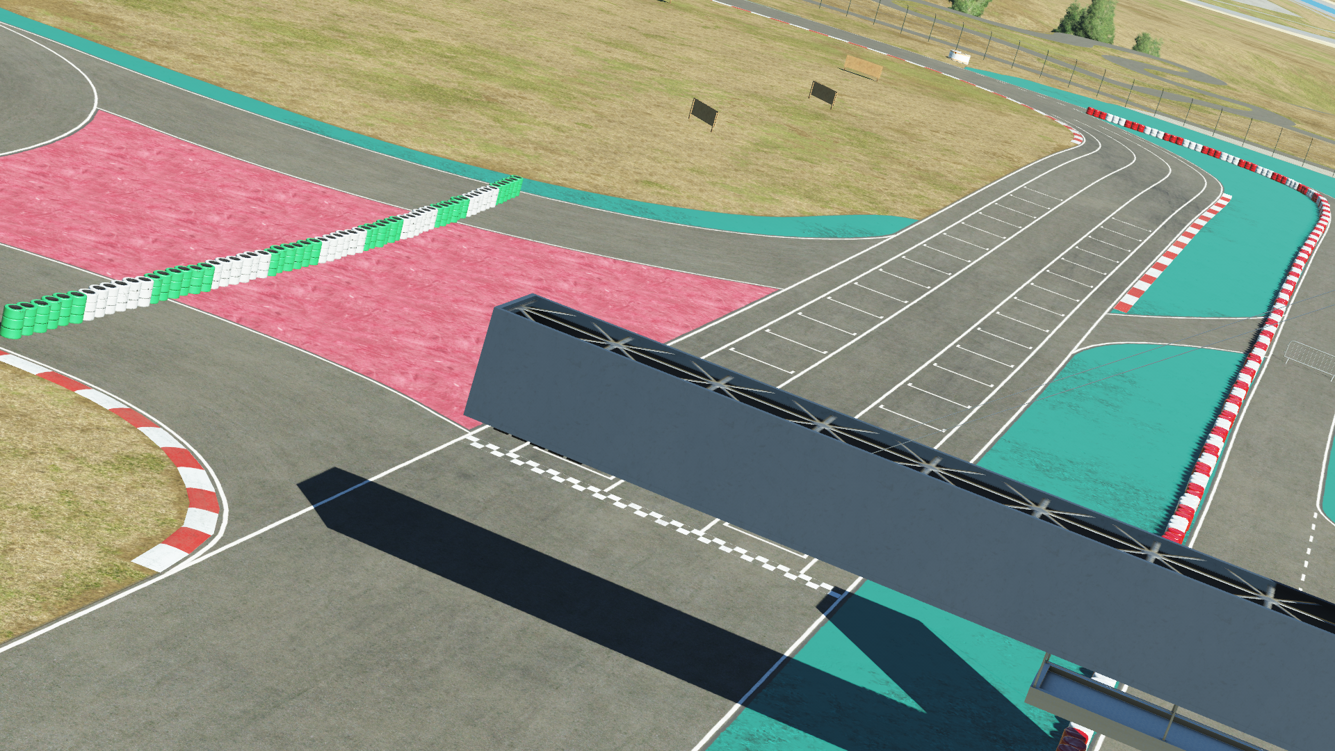 KartSim software rendering of Portimão kart track’s start–finish area underneath an overhead gantry, featuring grid-painted tarmac, turquoise and pink runoff zones, red-and-white kerbs, and dry grassy run-off beyond.