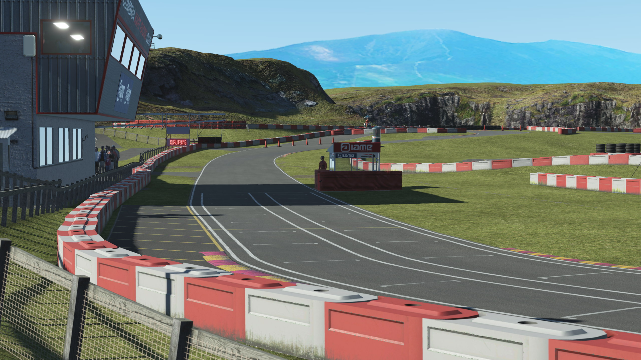 Start/finish straight at Rowrah in KartSim Pro UK, with pit building and control tower visible.