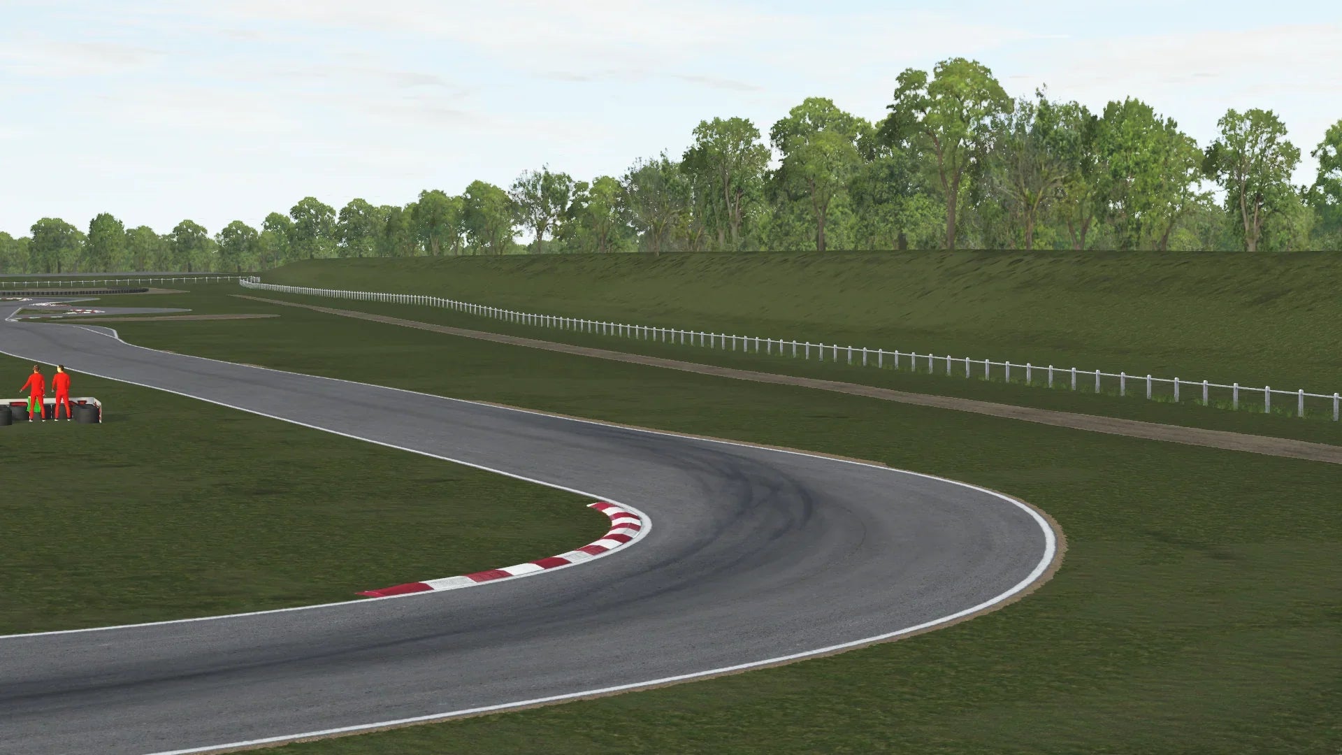 KartSim software rendering of the Salbris karting circuit showing a right-hand bend with red-white kerbs, tire stacks and track marshals in red overalls on the grass run-off, a white wooden fence lining the back straight, and a tree-lined embankment under a cloudy sky.