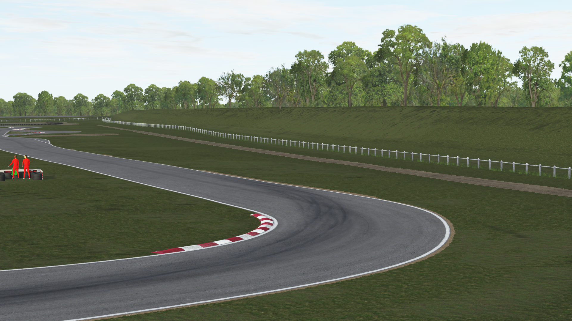 KartSim software rendering of the Salbris karting circuit showing a right-hand bend with red-white kerbs, tire stacks and track marshals in red overalls on the grass run-off, a white wooden fence lining the back straight, and a tree-lined embankment under a cloudy sky.
