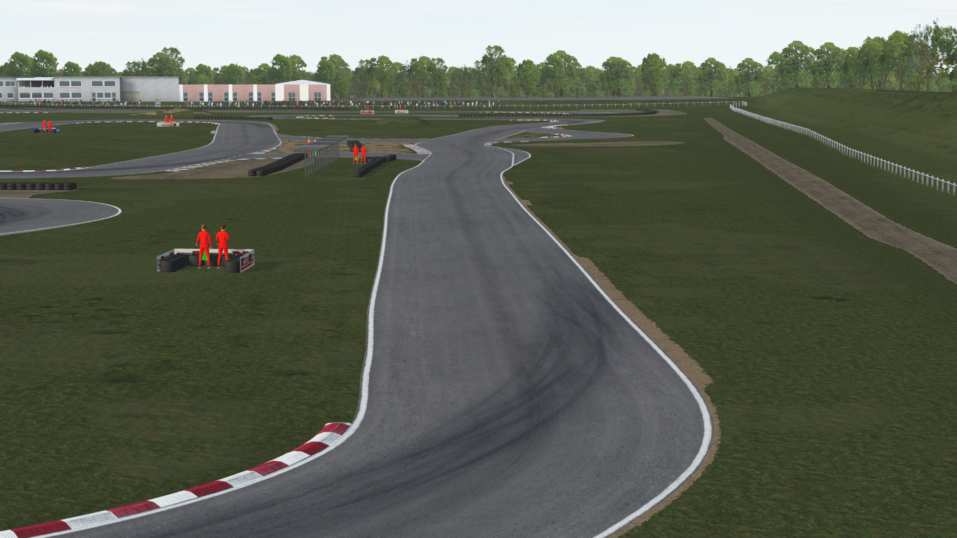 KartSim software rendering of the Salbris karting circuit, showing a sweeping left-hand corner with red-white kerbs, tire barriers on a gravel run-off, a line of spectators behind a guardrail