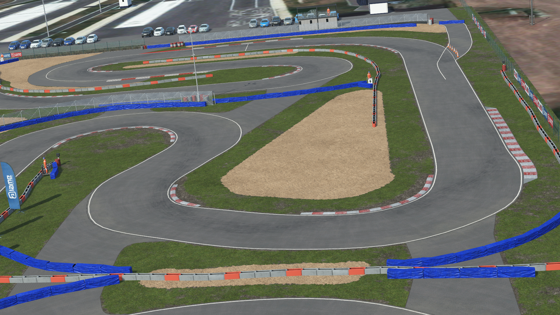 In-simulation panoramic view of the Slovakiaring karting circuit in KartSim software, showing the asphalt track with red-white kerbs, blue protective barriers, gravel run-off areas, pit buildings, paddock cars, and clear sky above.