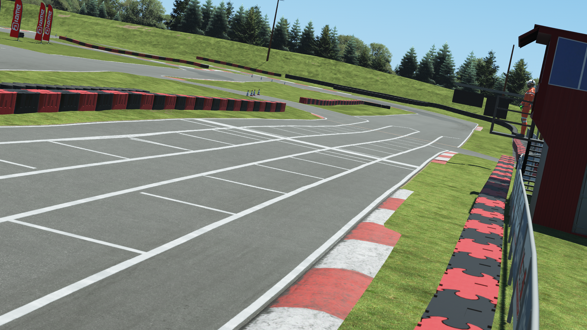 Virtual kart track start/finish grid with red-and-white curbs and grassy slopes