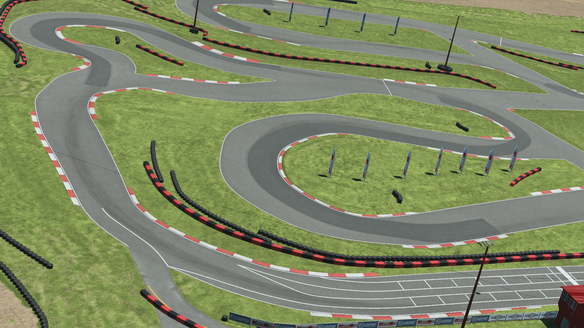 Aerial view of a winding kart racing circuit with red-and-white curbs, grass infield, and blue sponsor flags