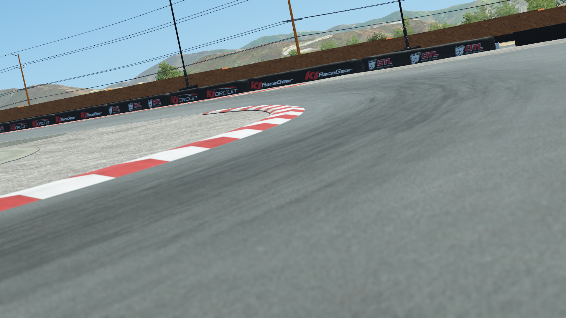 K1 Winchester kart track corner – red and white apex curb, branded safety barriers, and desert hills under clear sky