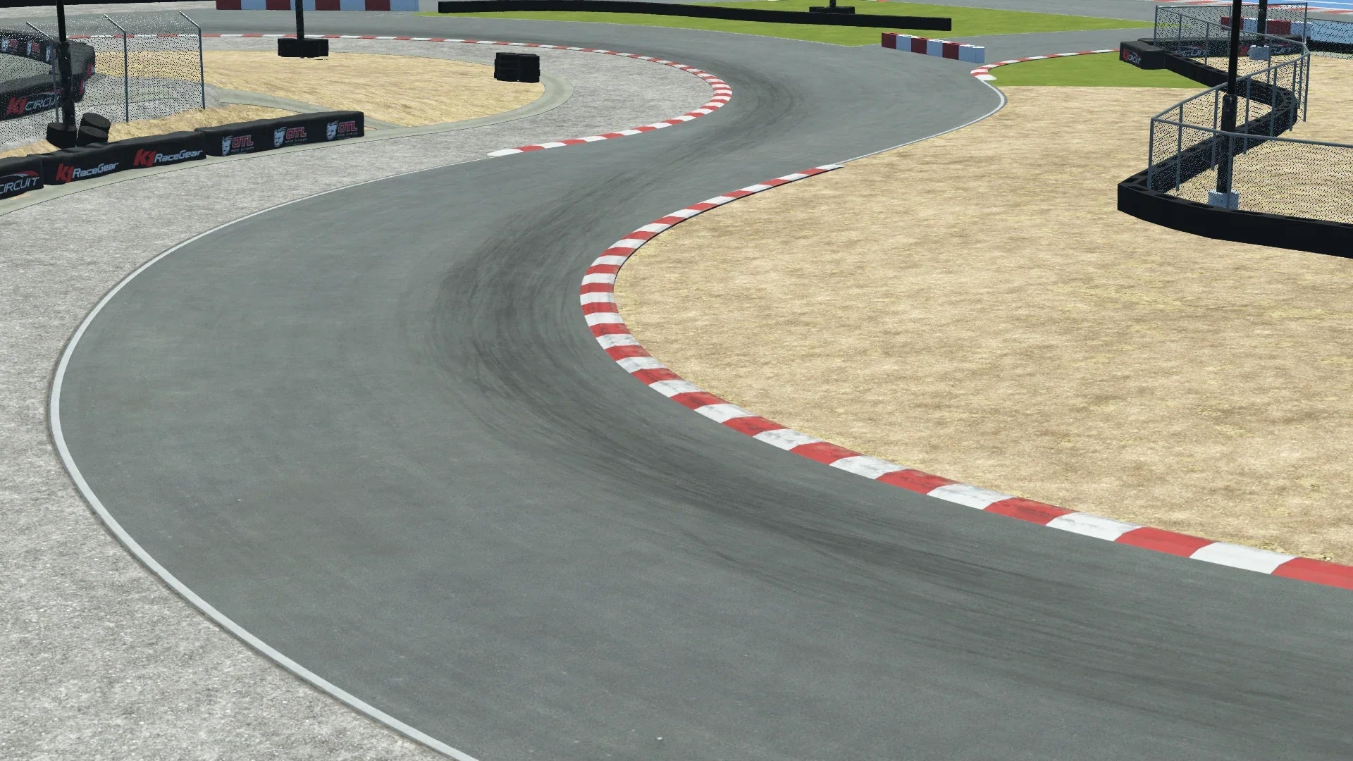K1 Winchester karting circuit corner – red and white curb, tire barriers, sandy runoff, and protective fencing
