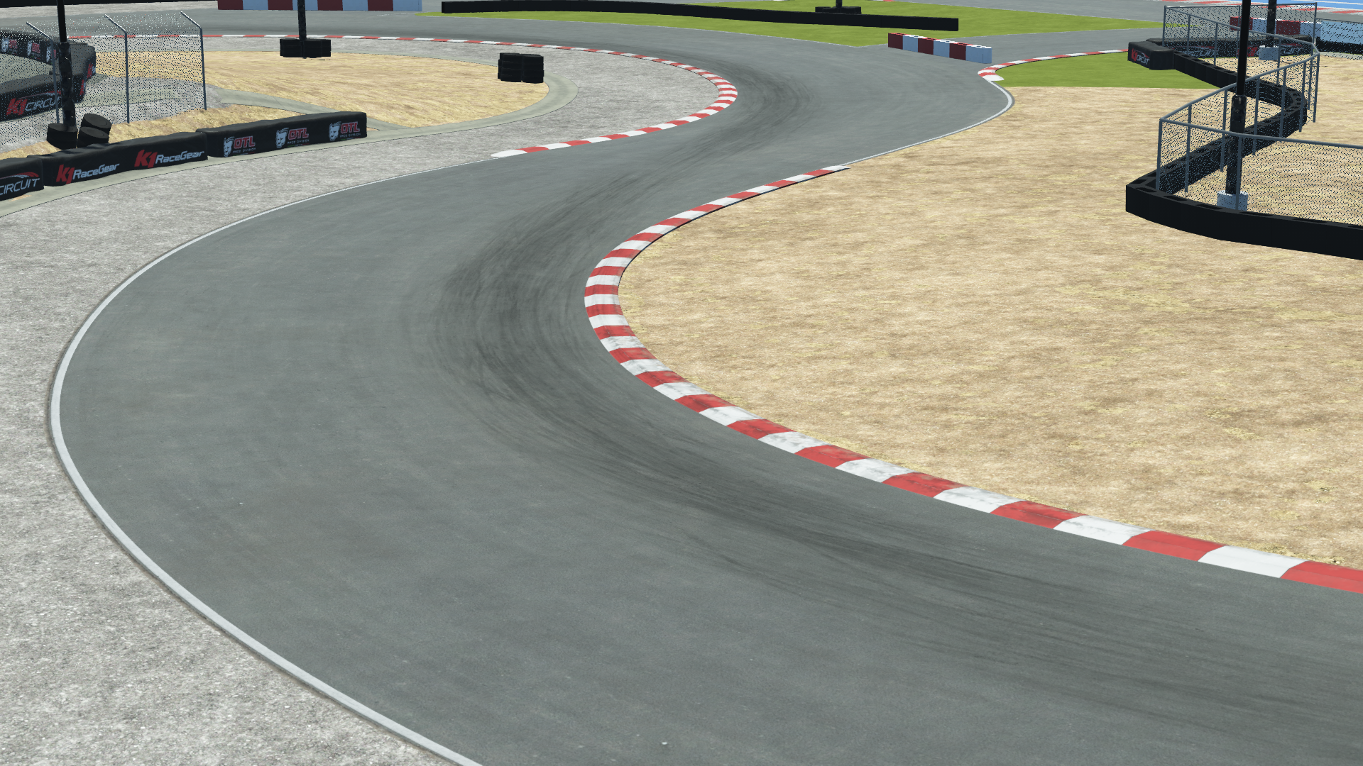 K1 Winchester karting circuit corner – red and white curb, tire barriers, sandy runoff, and protective fencing