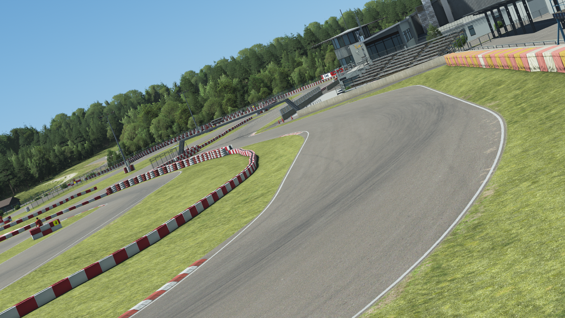 Angled in-simulation view of the Wackersdorf karting circuit in KartSim software, showing the asphalt racing line with red-white kerbs, grass run-off areas, spectator stands, and surrounding forest under a clear blue sky.