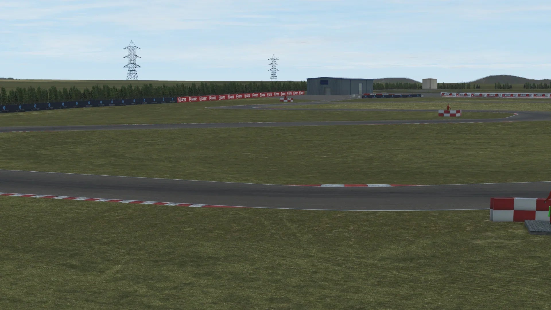 Panoramic in-simulation view of the Zuera karting circuit in KartSim software, showing the asphalt track with red-white curbs, grass run-off areas, barrier fencing, pit buildings, and clear sky above.