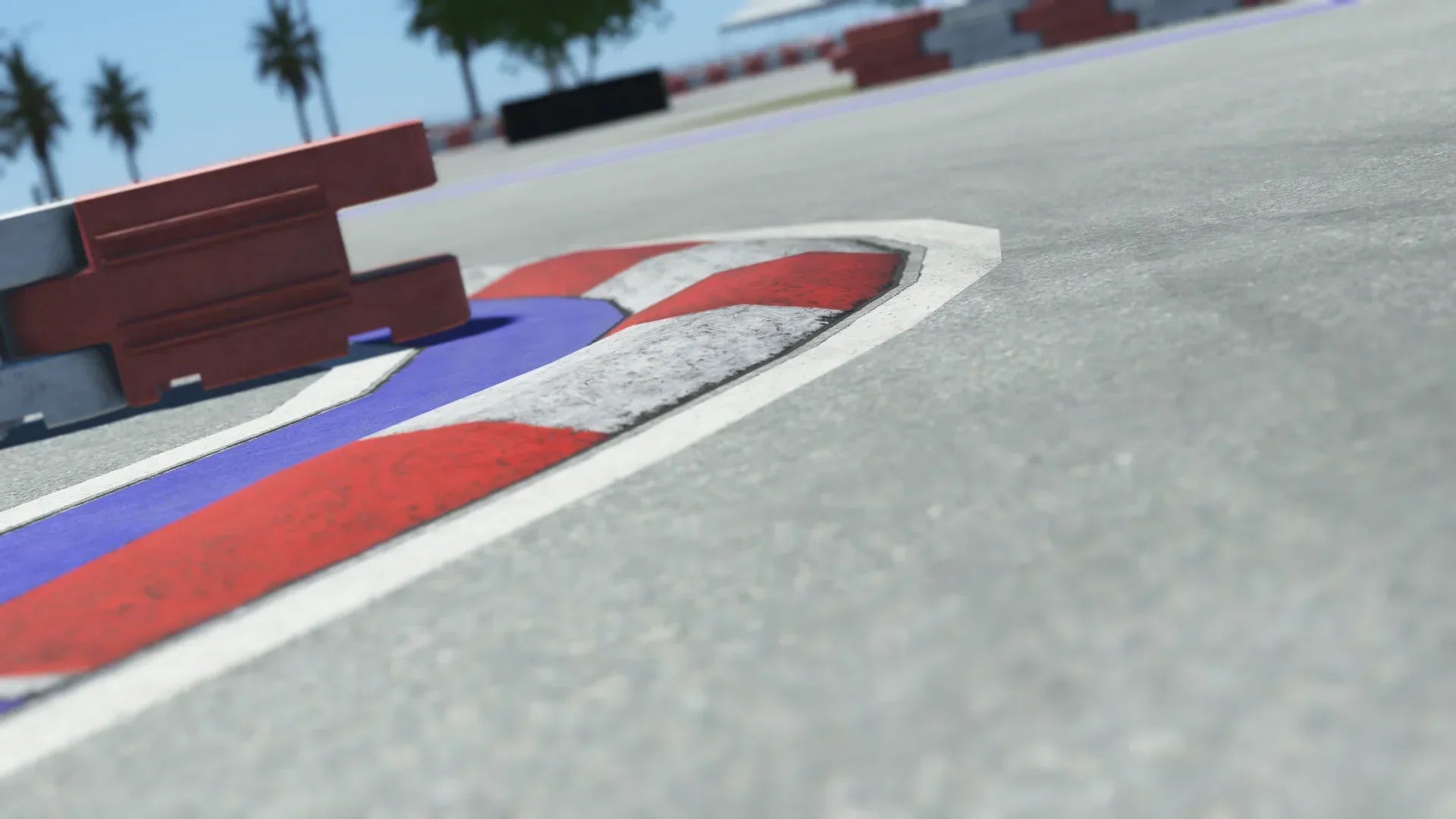 Close-up of red, white, and blue curb on a Miami race track with safety barriers and palm trees in background