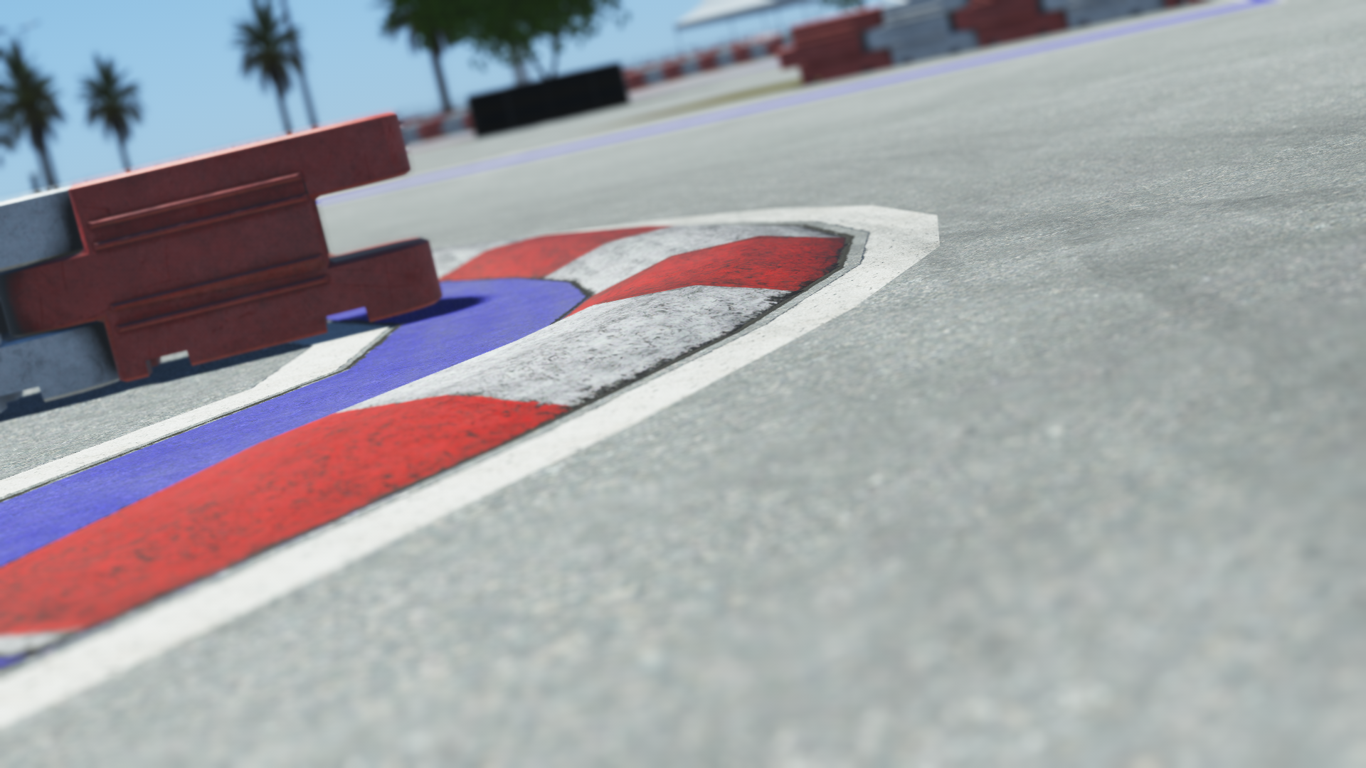 Close-up of red, white, and blue curb on a Miami race track with safety barriers and palm trees in background