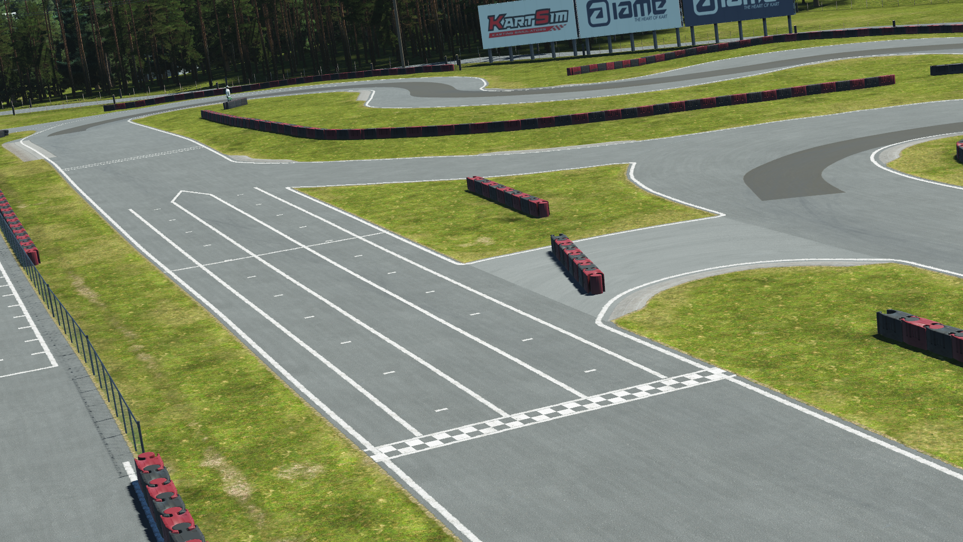 View of Mosport karting track start/finish line with pit lanes, tarmac surface, and grassy surroundings under clear skies