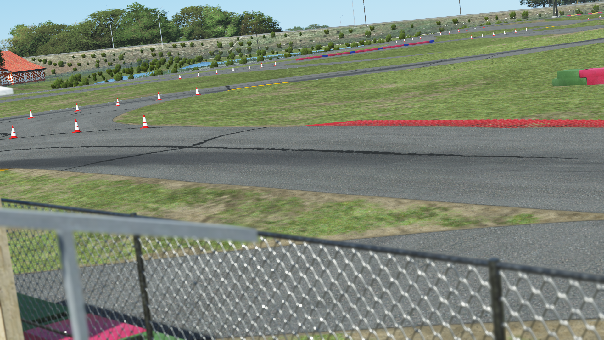 New Castle race track with safety cones, grass run-off, and fencing in foreground