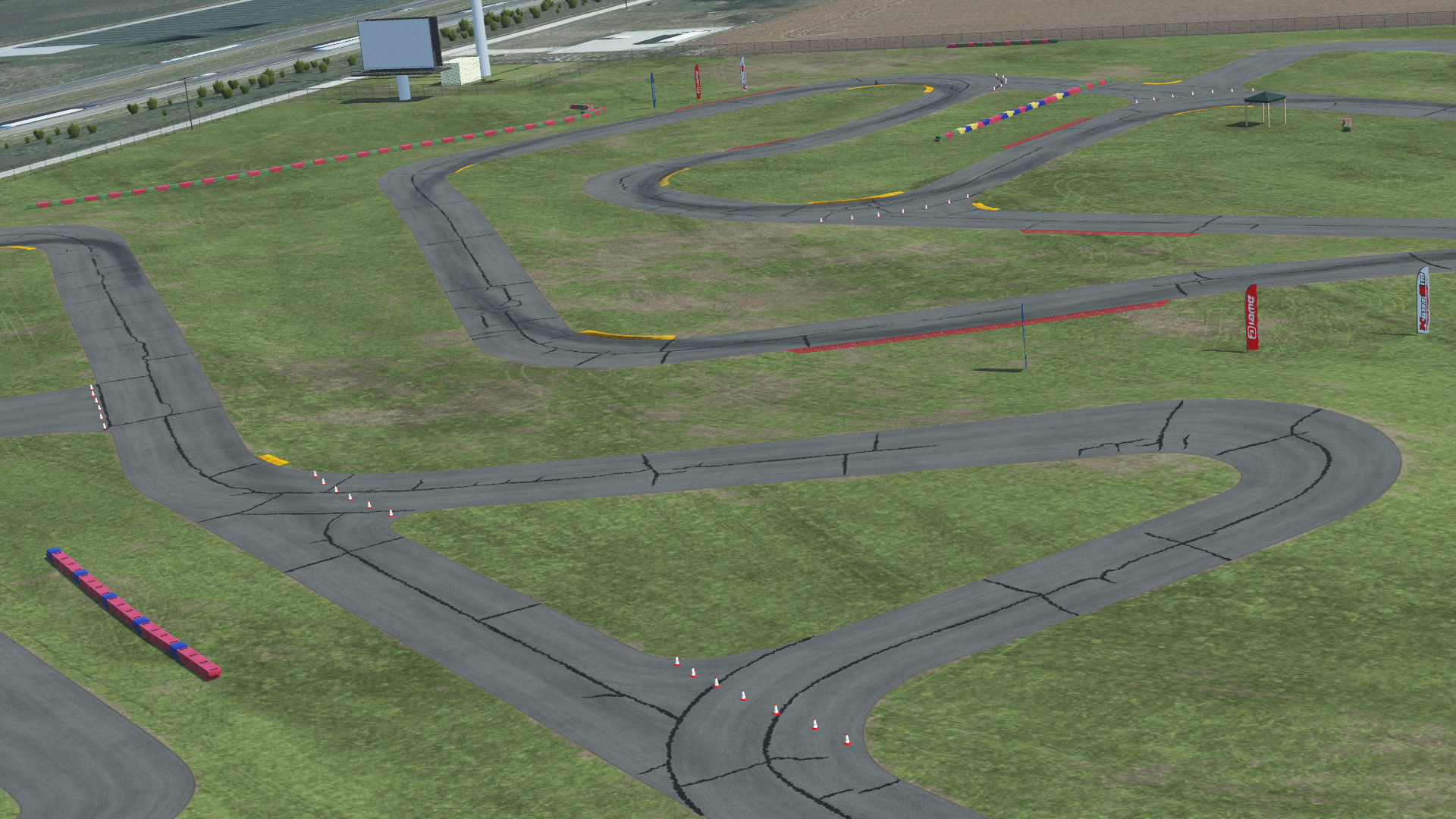 Overhead view of New Castle karting circuit with asphalt track, grassy infield, cones, and safety barriers