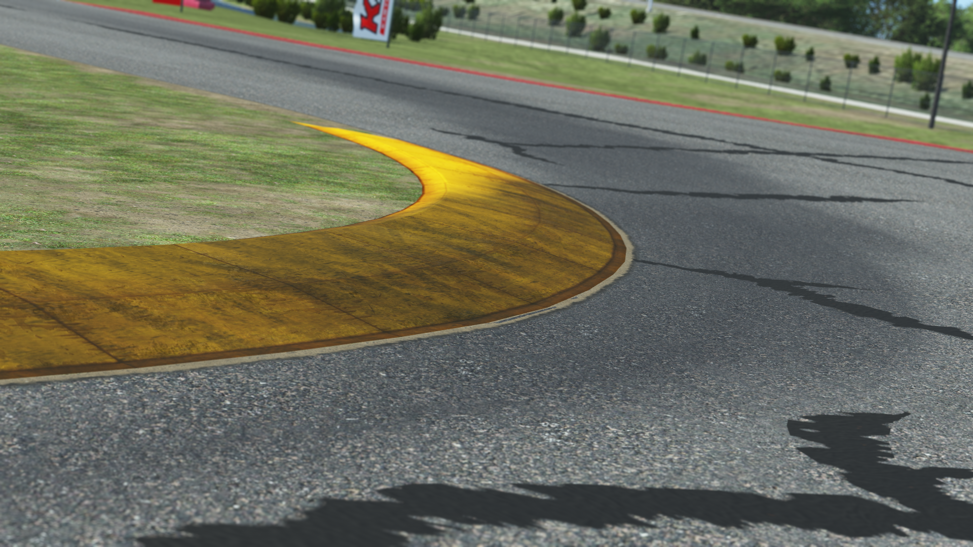 Close-up of a race track corner with yellow kerb and visible tarmac cracks
