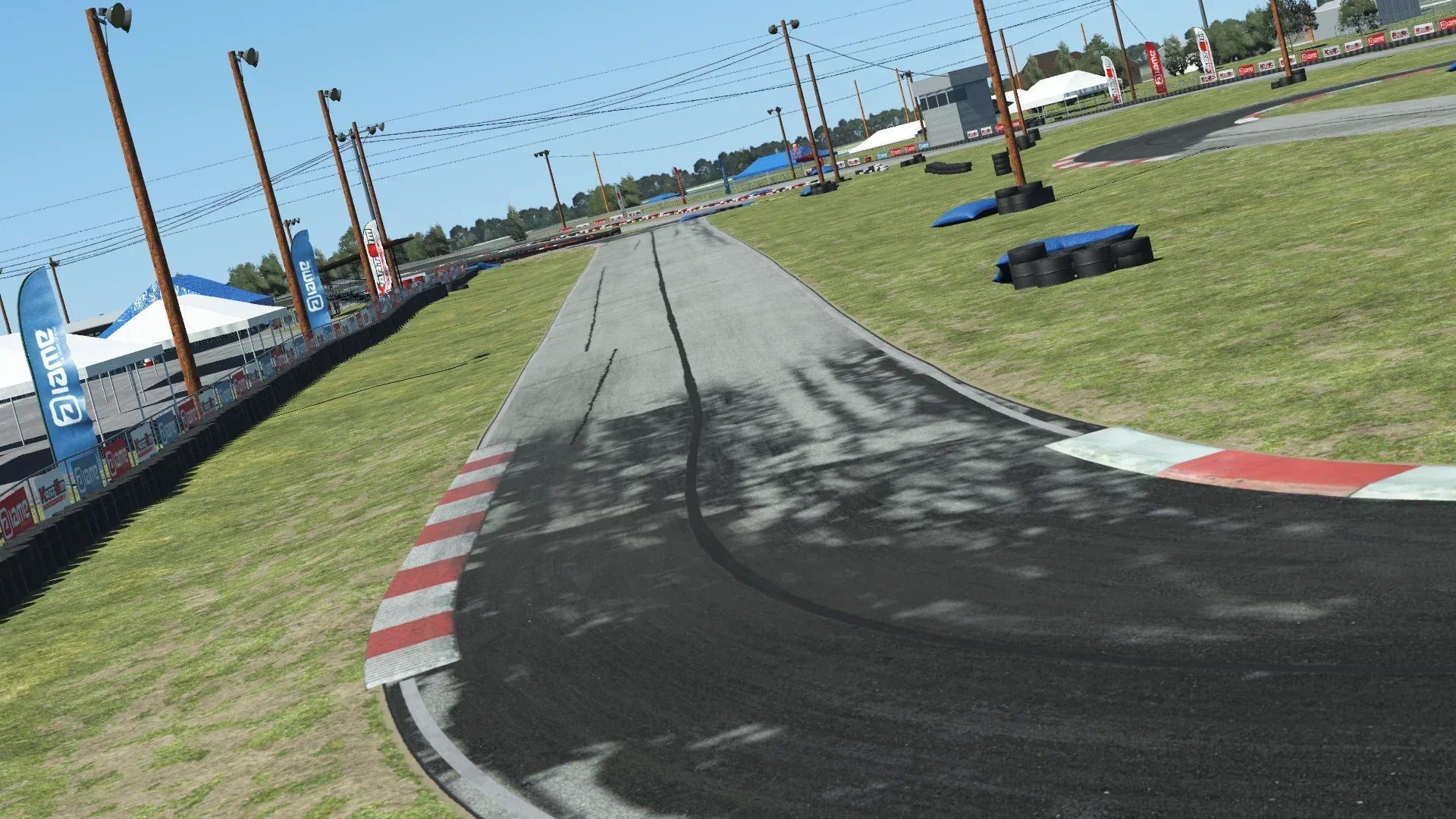 Go-kart track with red and white curbs, tire barriers, and sponsor banners on a clear day at North Texas circuit