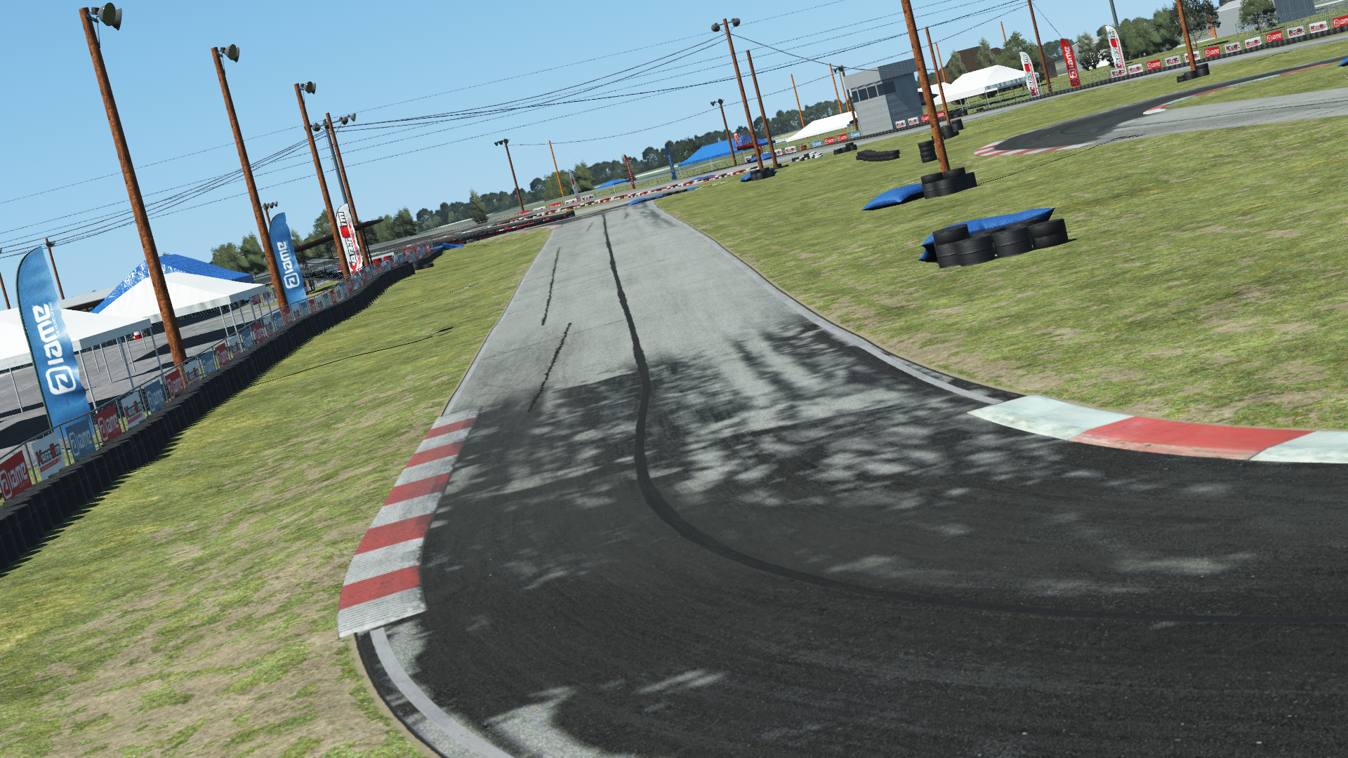 Go-kart track with red and white curbs, tire barriers, and sponsor banners on a clear day at North Texas circuit