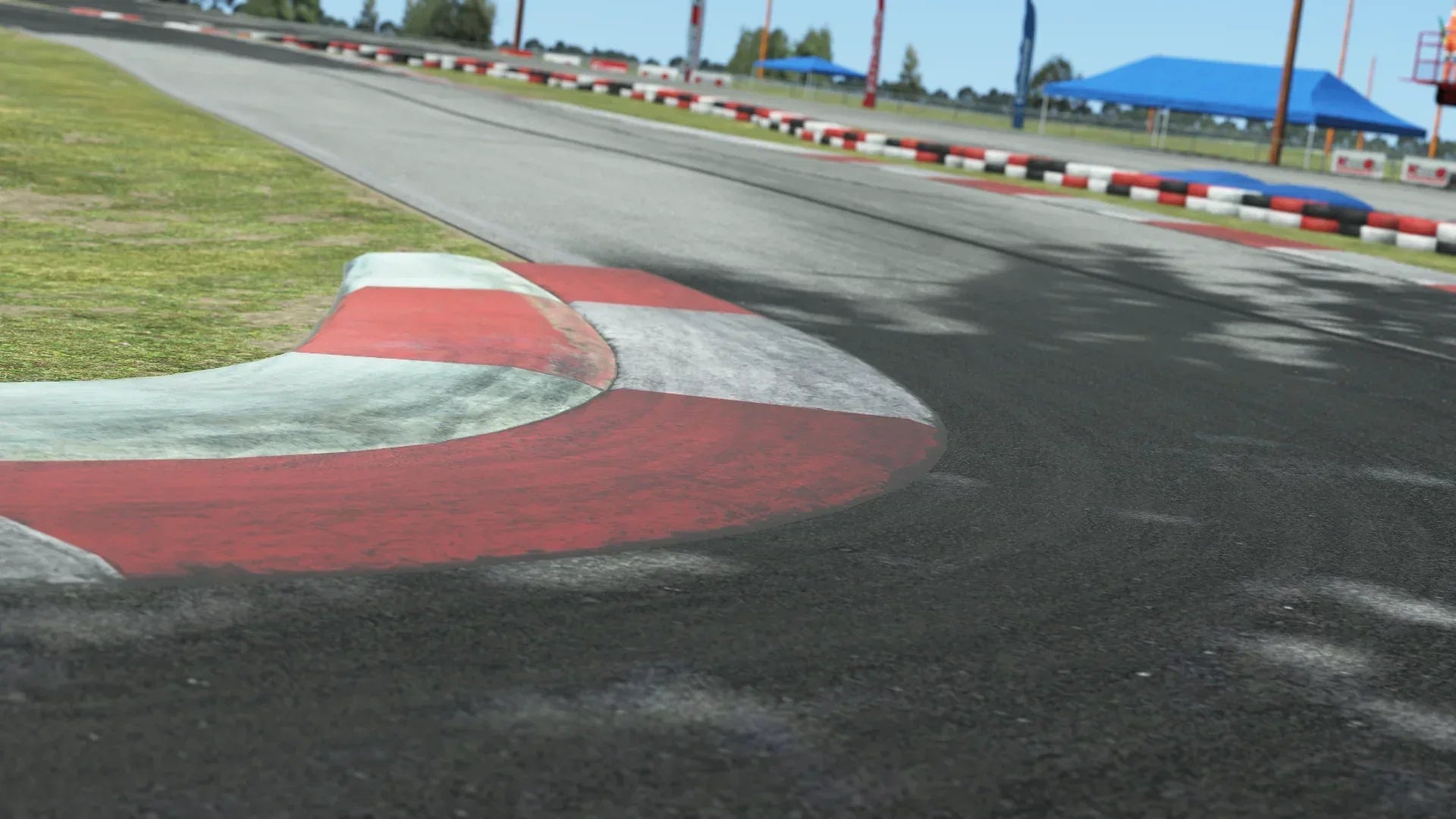 Close-up of red and white curb on North Texas go-kart track with tire marks and grassy edge