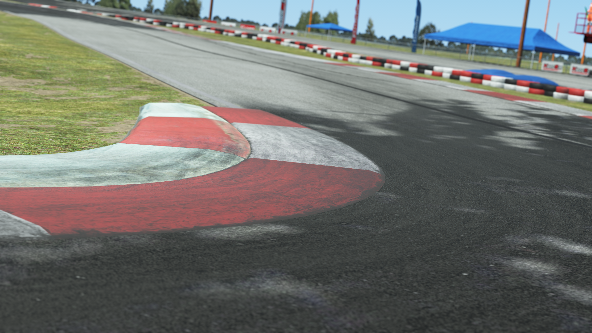Close-up of red and white curb on North Texas go-kart track with tire marks and grassy edge