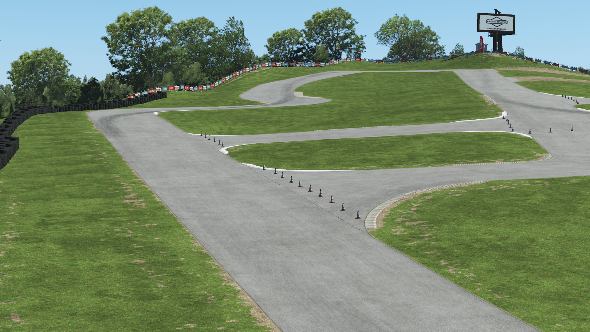 Karting circuit with elevation changes and lush grass surroundings under a blue sky