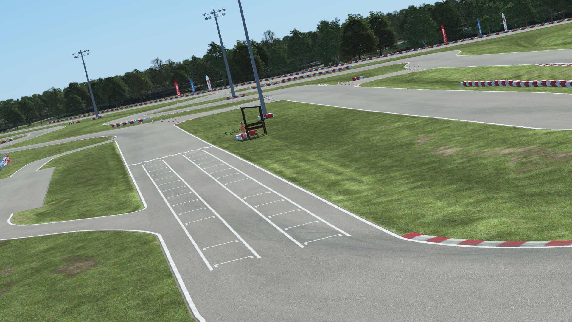 Speedsportz karting circuit with starting grid lines, red and white curbs, and surrounding trees under a clear sky