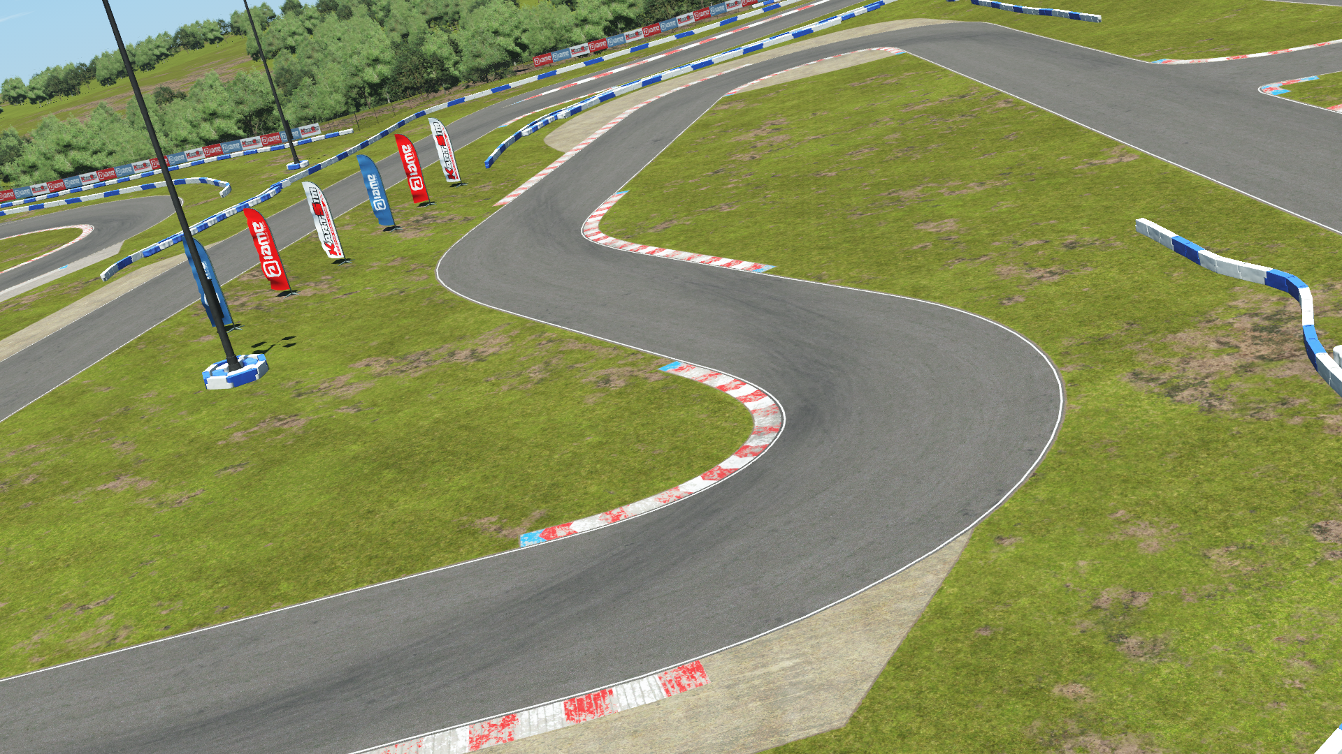 Curving karting track with red and white kerbs, grass infield, and sponsor flags