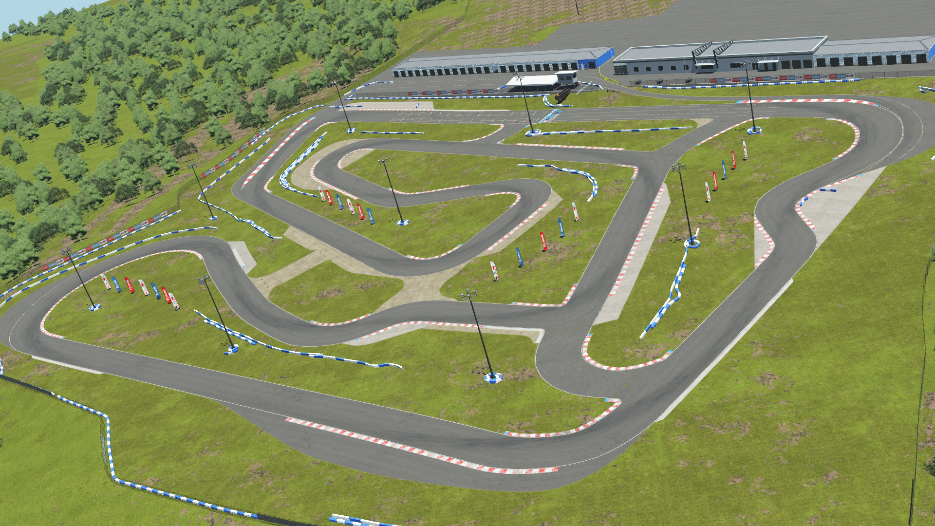Aerial view of a karting circuit with surrounding green grass, light poles, and buildings in the background